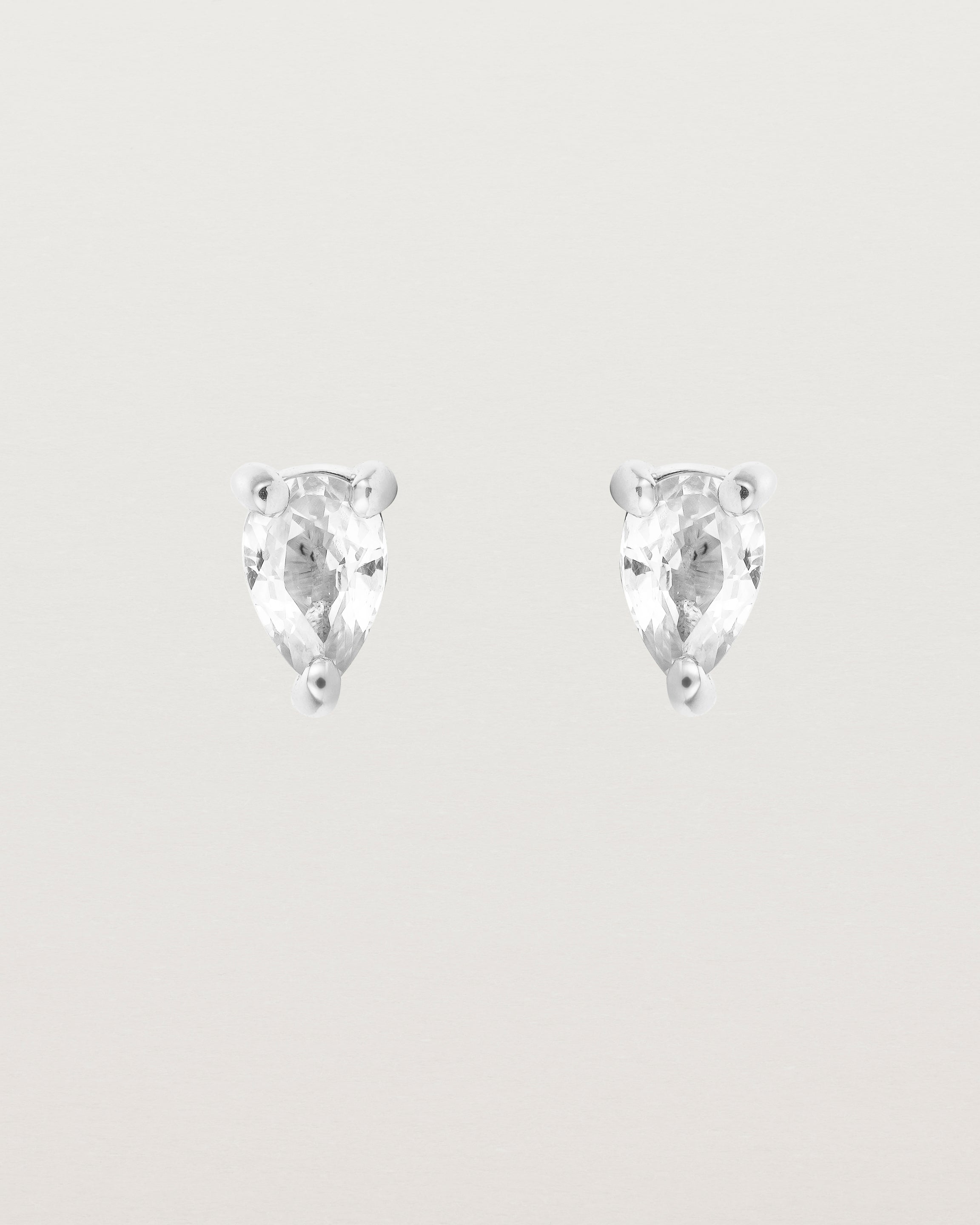 a pair of white gold studs featuring a pear cut diamond