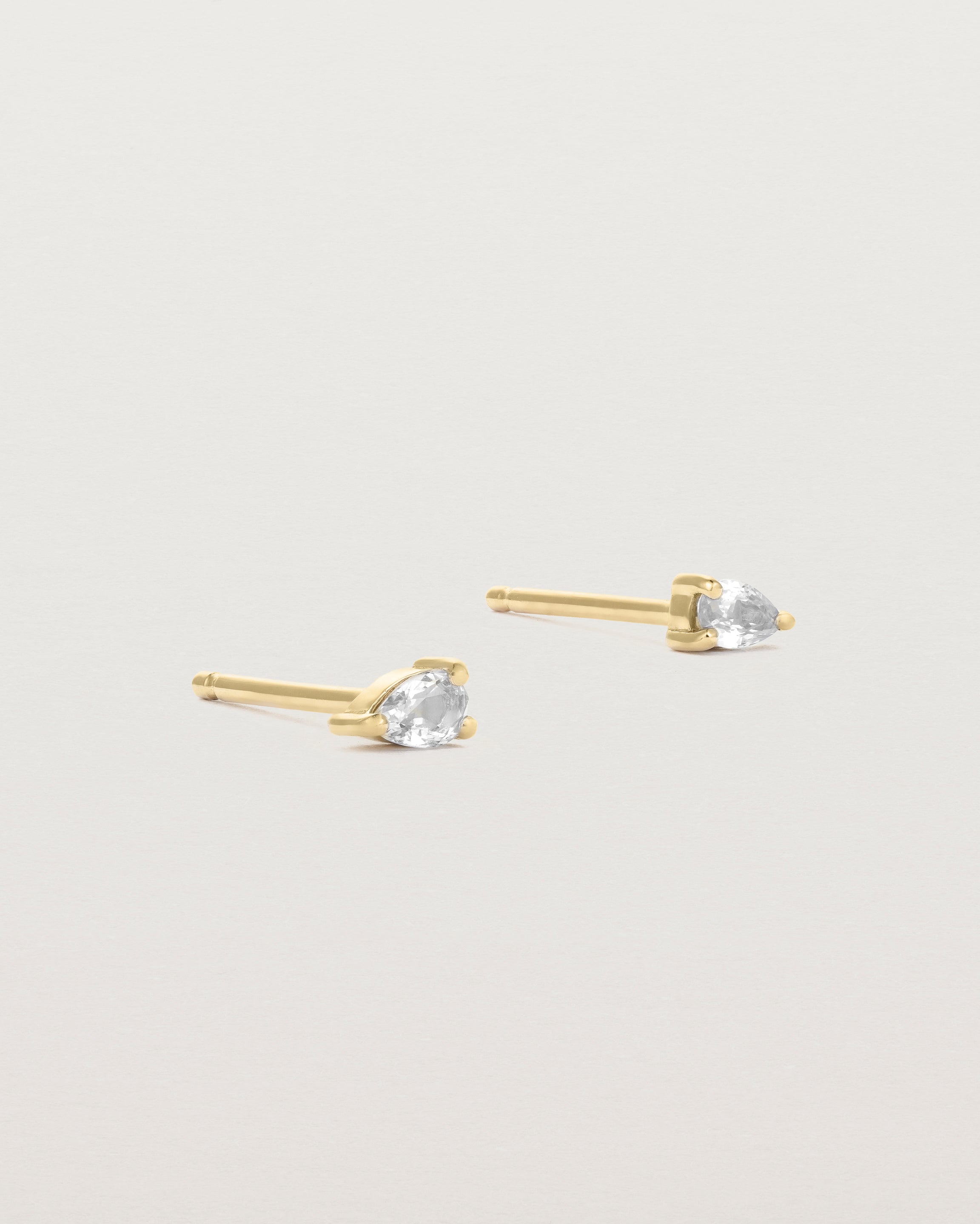 a pair of yellow gold studs featuring a pear cut diamond