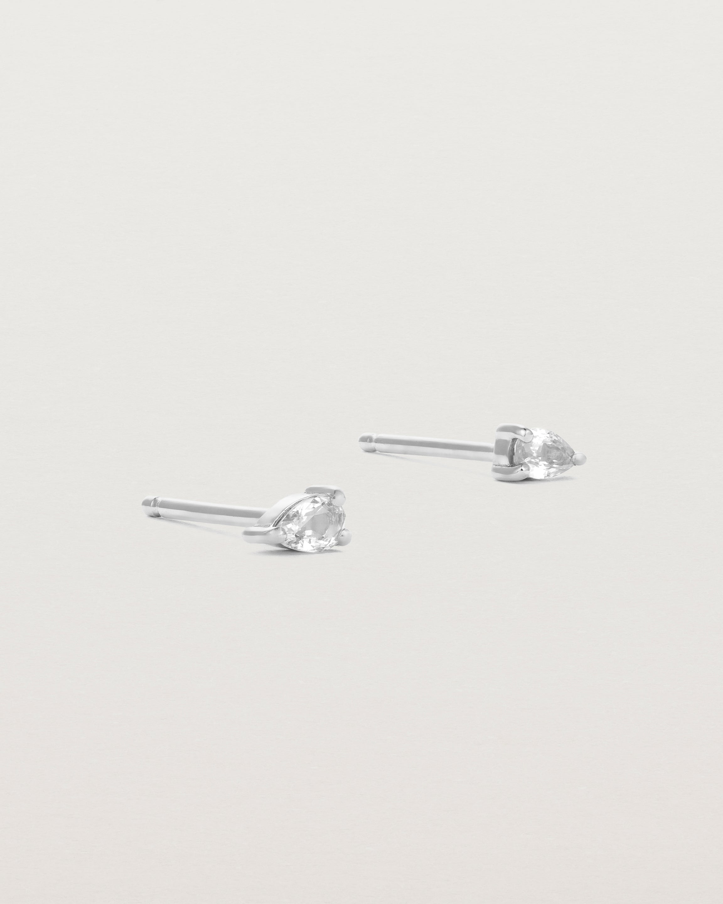 a pair of white gold studs featuring a pear cut diamond