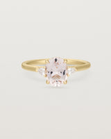 An oval morganite adorned with white diamonds either side, featuring a sweeping setting and crafted in yellow gold