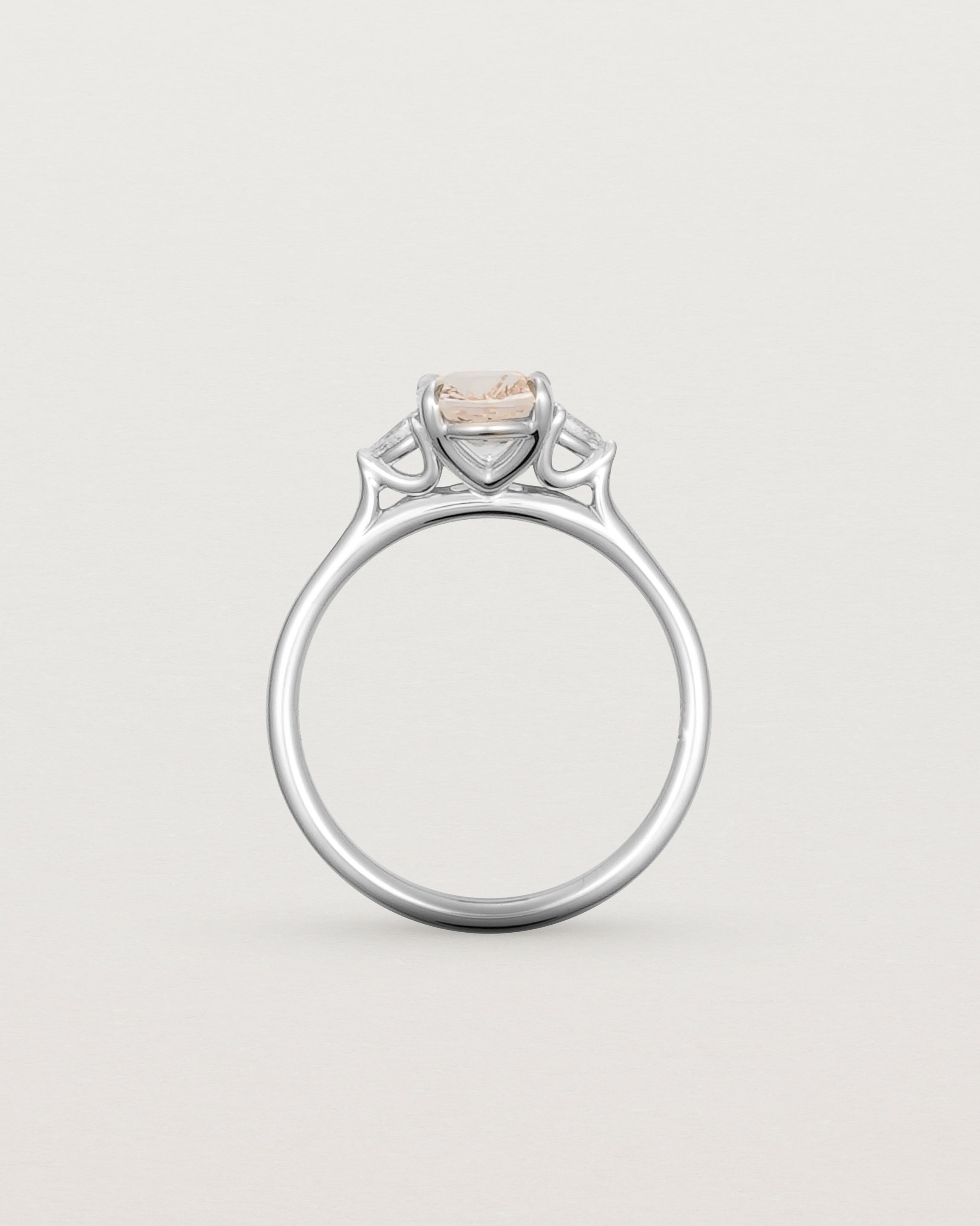 The side profile of an oval morganite adorned with two white diamonds either side, featuring a sweeping setting and crafted in white gold