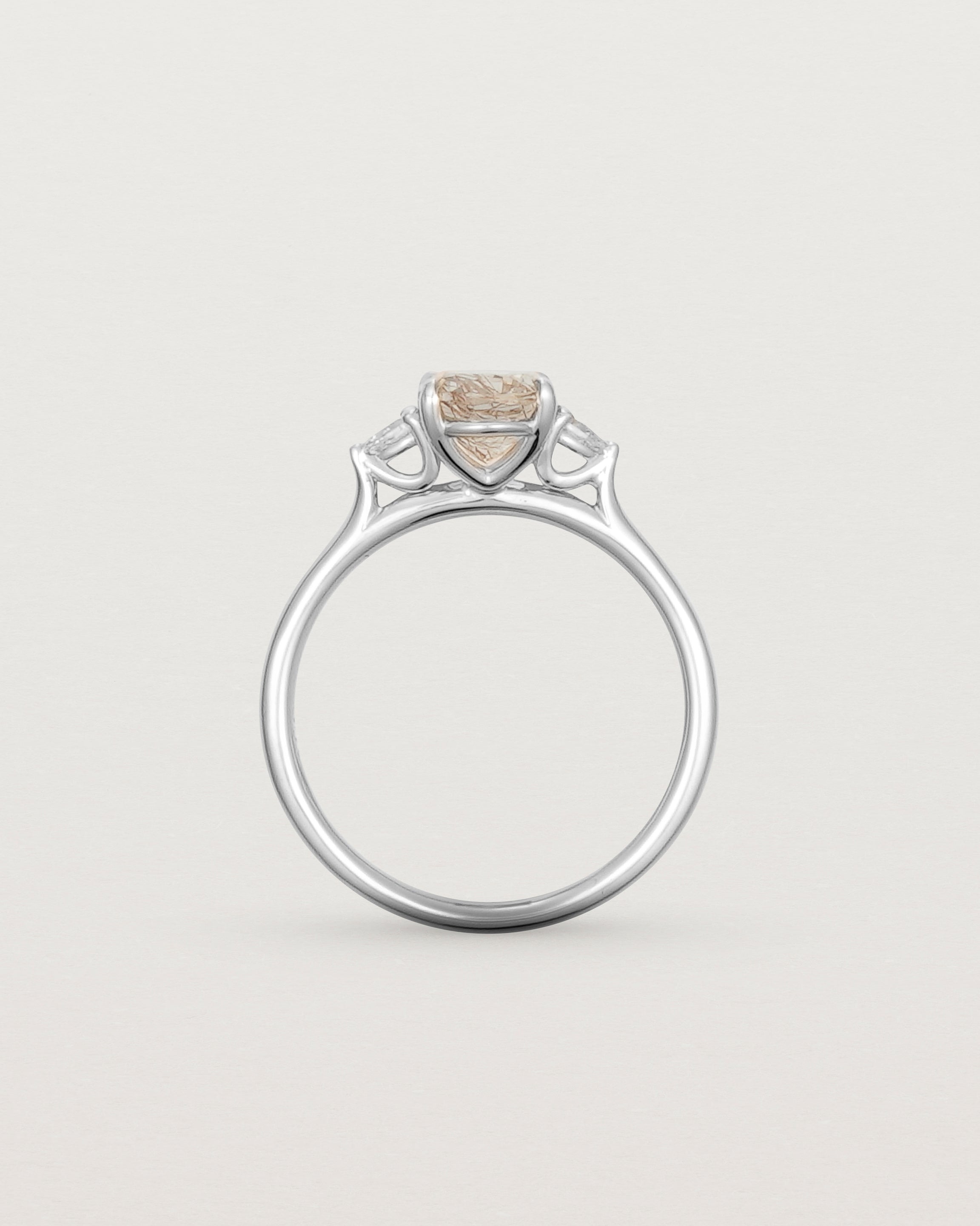 The side profile of an oval Rutilated Quartz adorned with white diamonds either side, featuring a sweeping setting and crafted in white gold