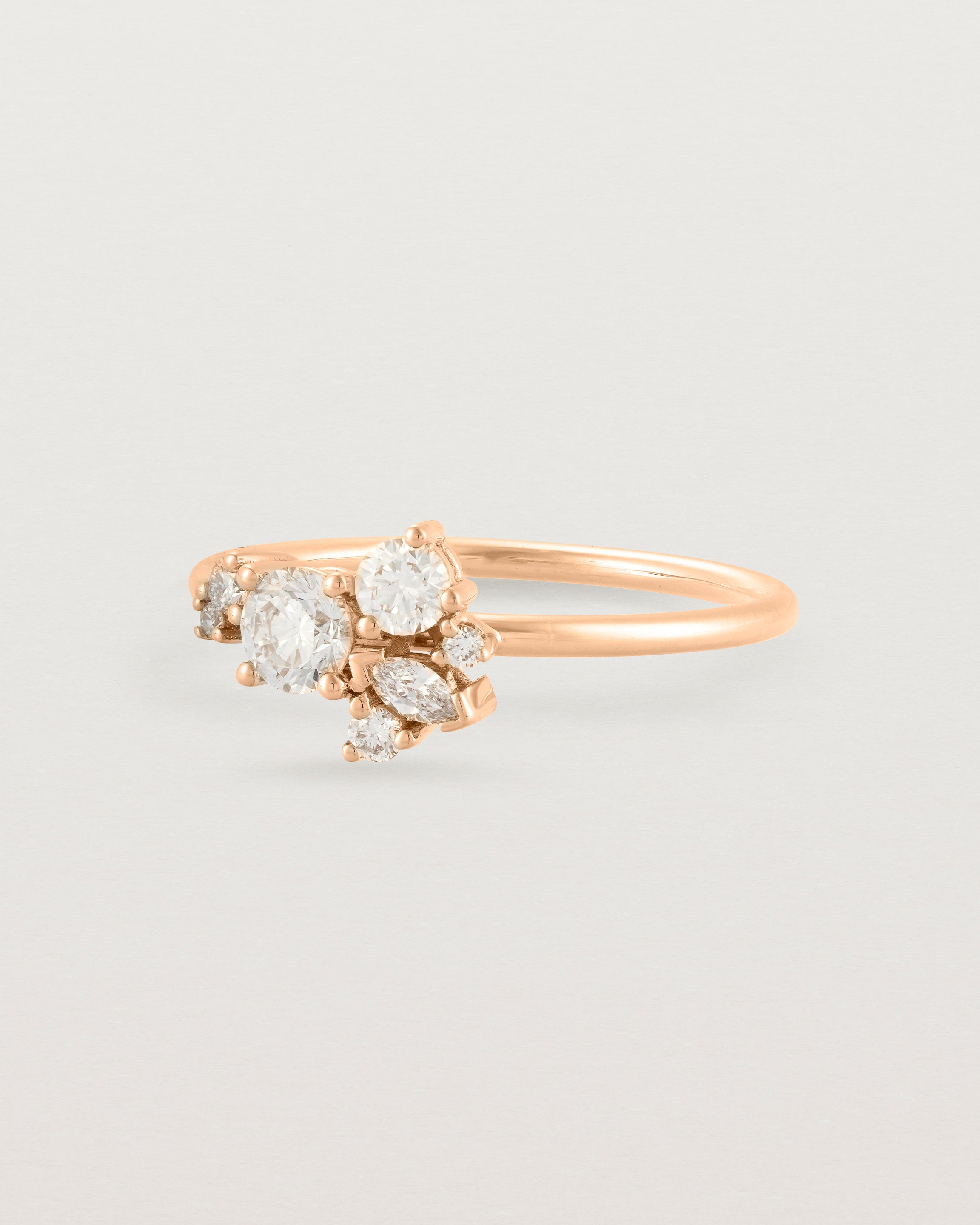 Side view of a white diamond cluster ring in rose gold