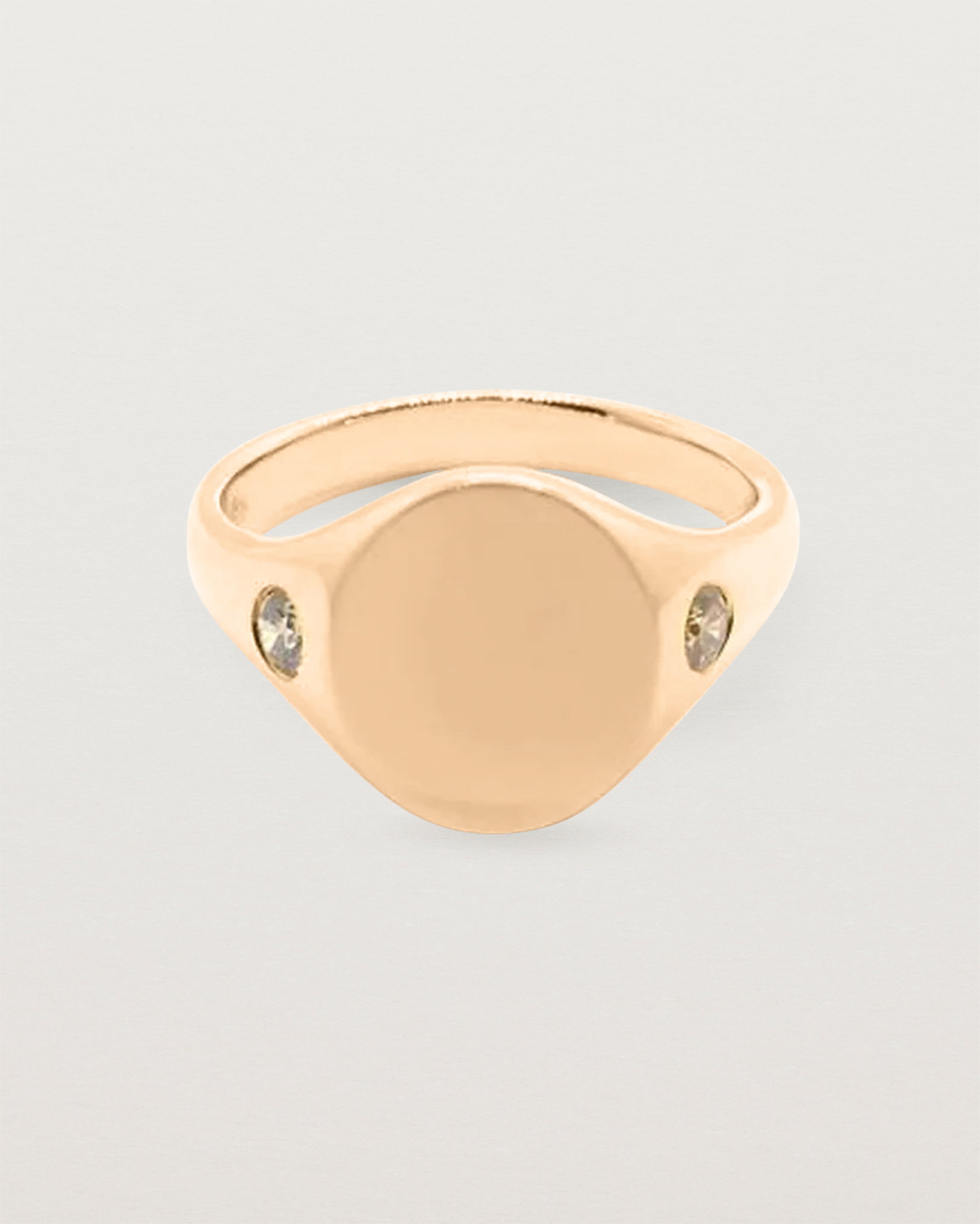 An oval signet with one diamond set on each shoulder in rose gold