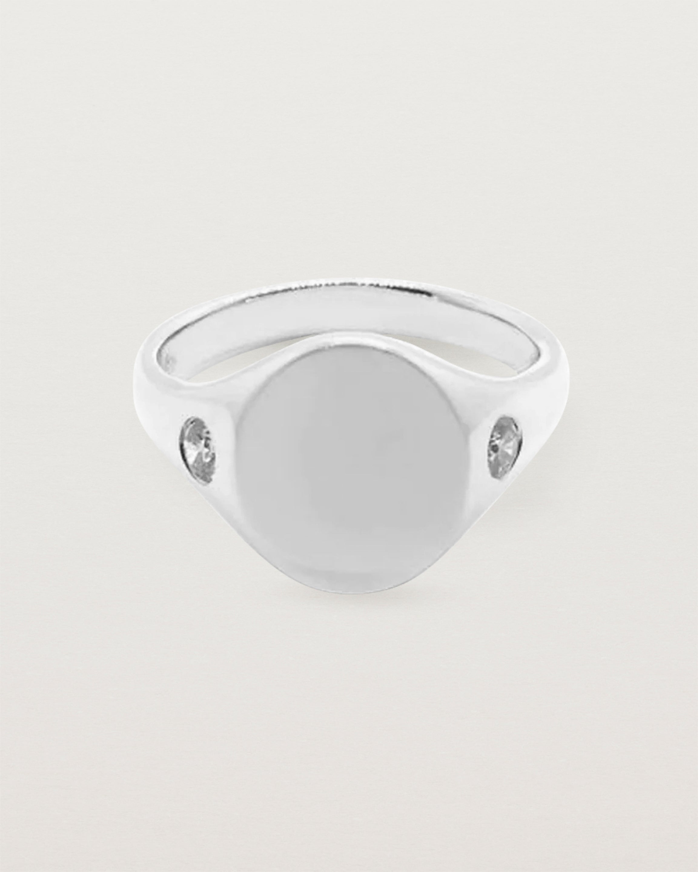 An oval signet with one diamond set on each shoulder in WHITE gold