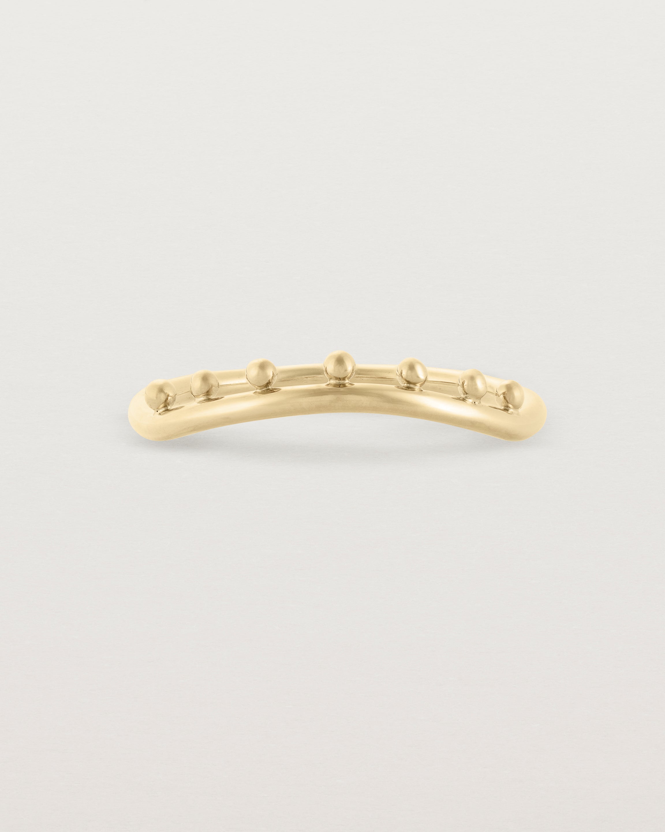 A gentle arc ring with dot detailing along the top of the arc, crafted in yellow gold