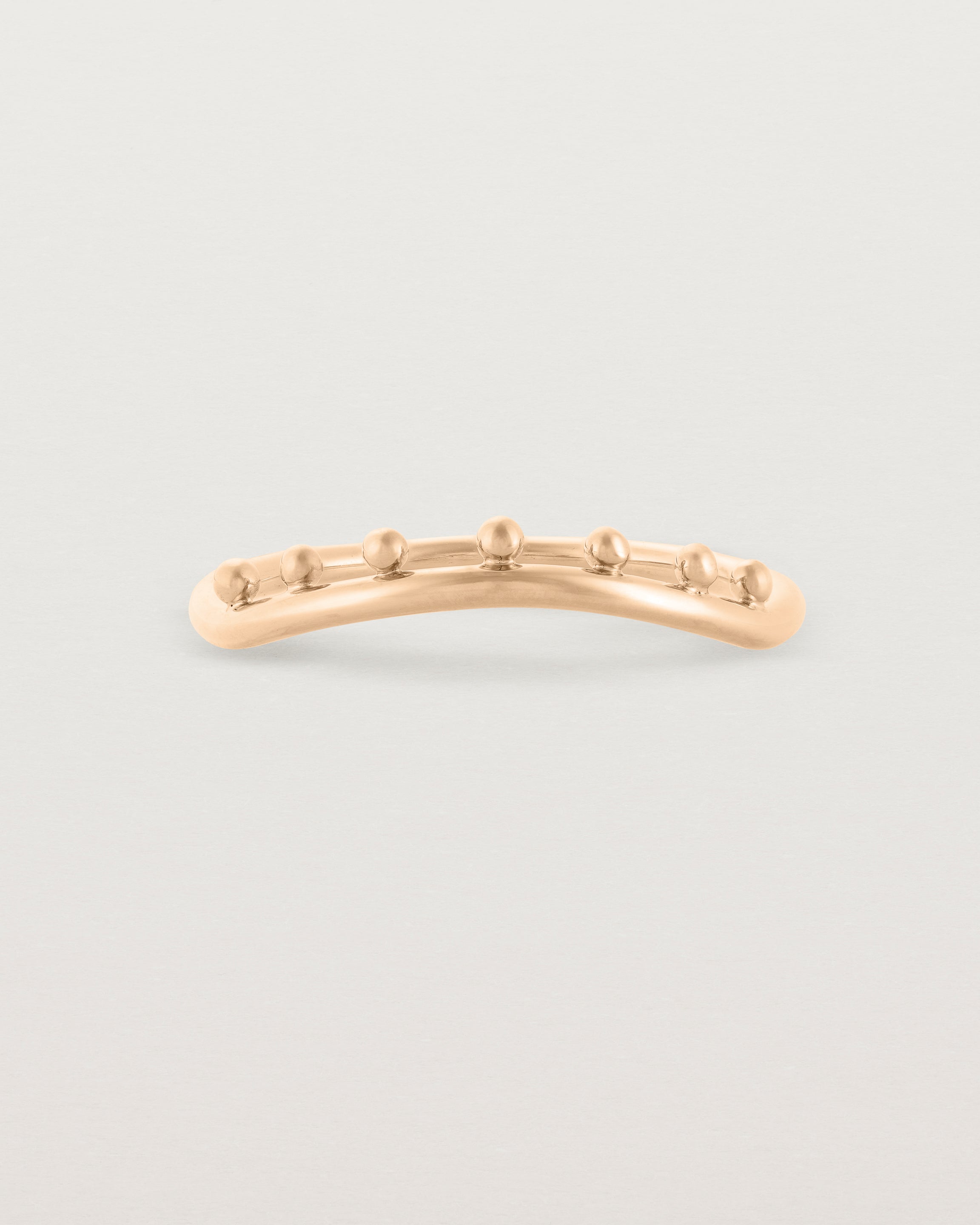 A gentle arc ring featuring dot detailing along the top of the arc, crafted in rose gold.