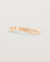 Side view of a gentle arc ring featuring dot detailing along the top of the arc, crafted in rose gold.