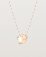 A molten textured rose gold disc with dots around the circumstance on a rose gold fine chain necklace