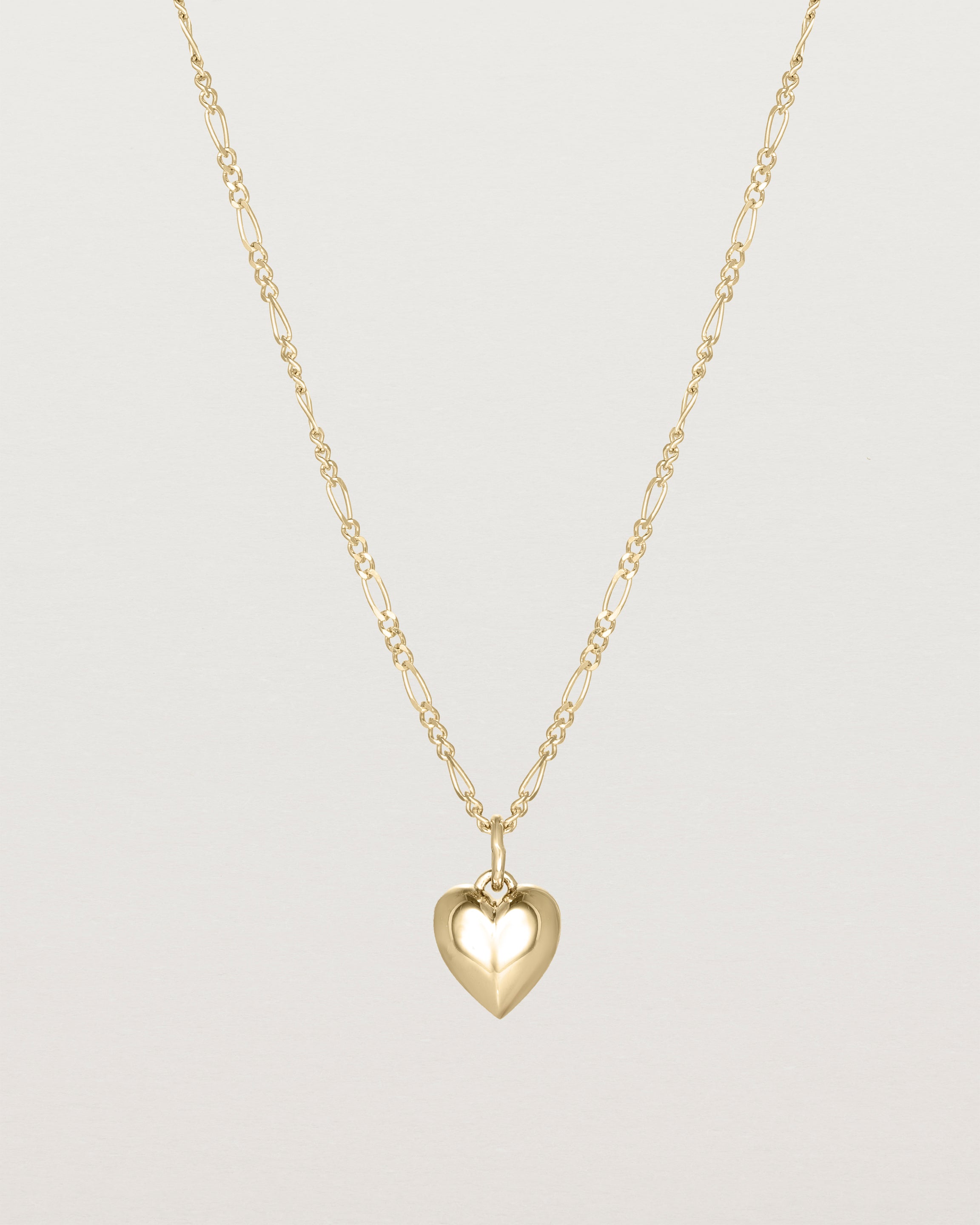 A solid heart is suspended from our fine Figaro Chain in yellow gold