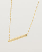 side view of Ellipse necklace with a yellow gold bar hanging from a chain in yellow gold
