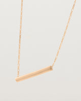 side view of Ellipse necklace with a rose gold bar hanging from a chain in rose gold