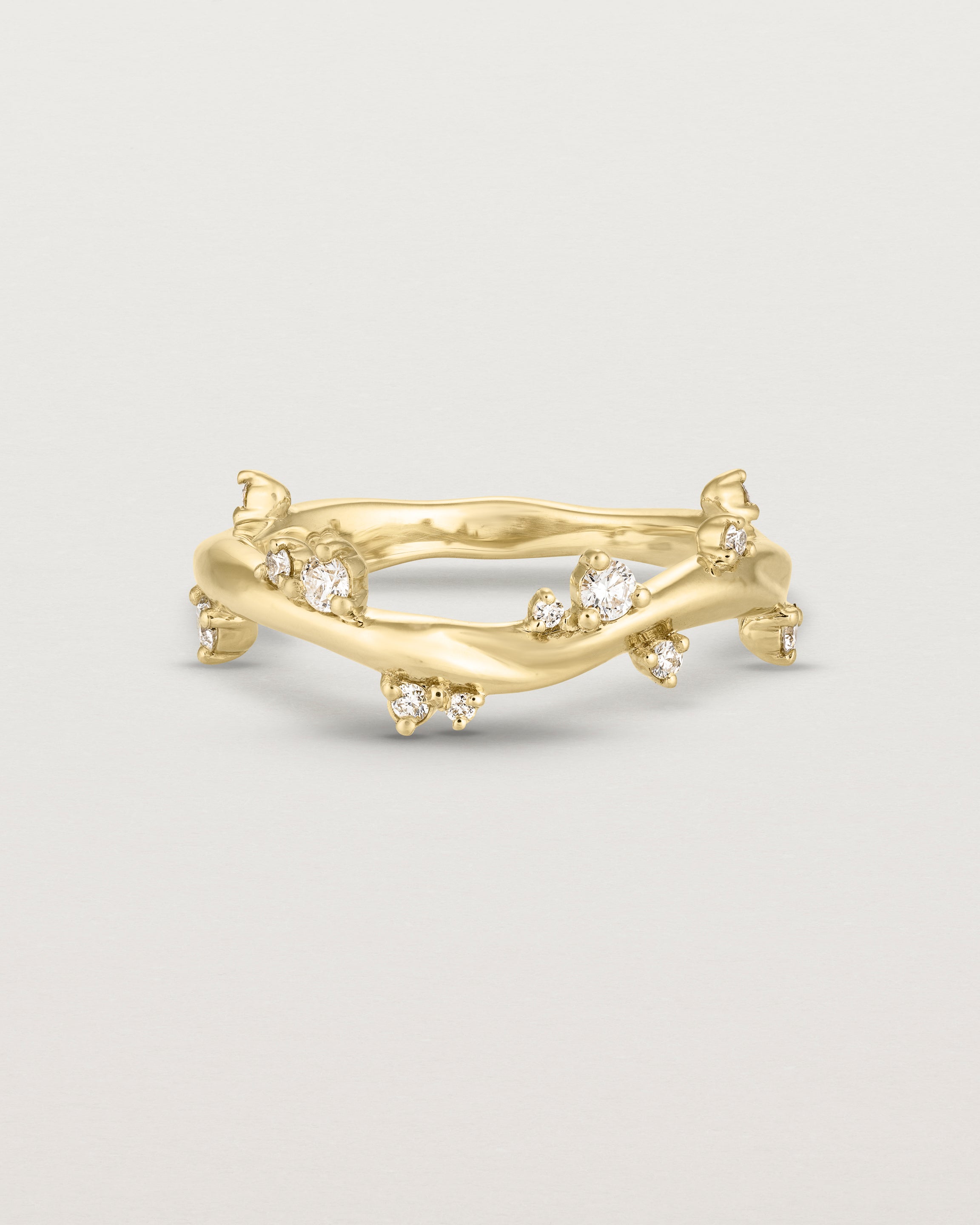 Product photo of the yellow gold Ember ring with white diamonds scattered around the band.