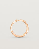 Product photo of the rose gold Ember ring with white diamonds scattered around the band standing up.