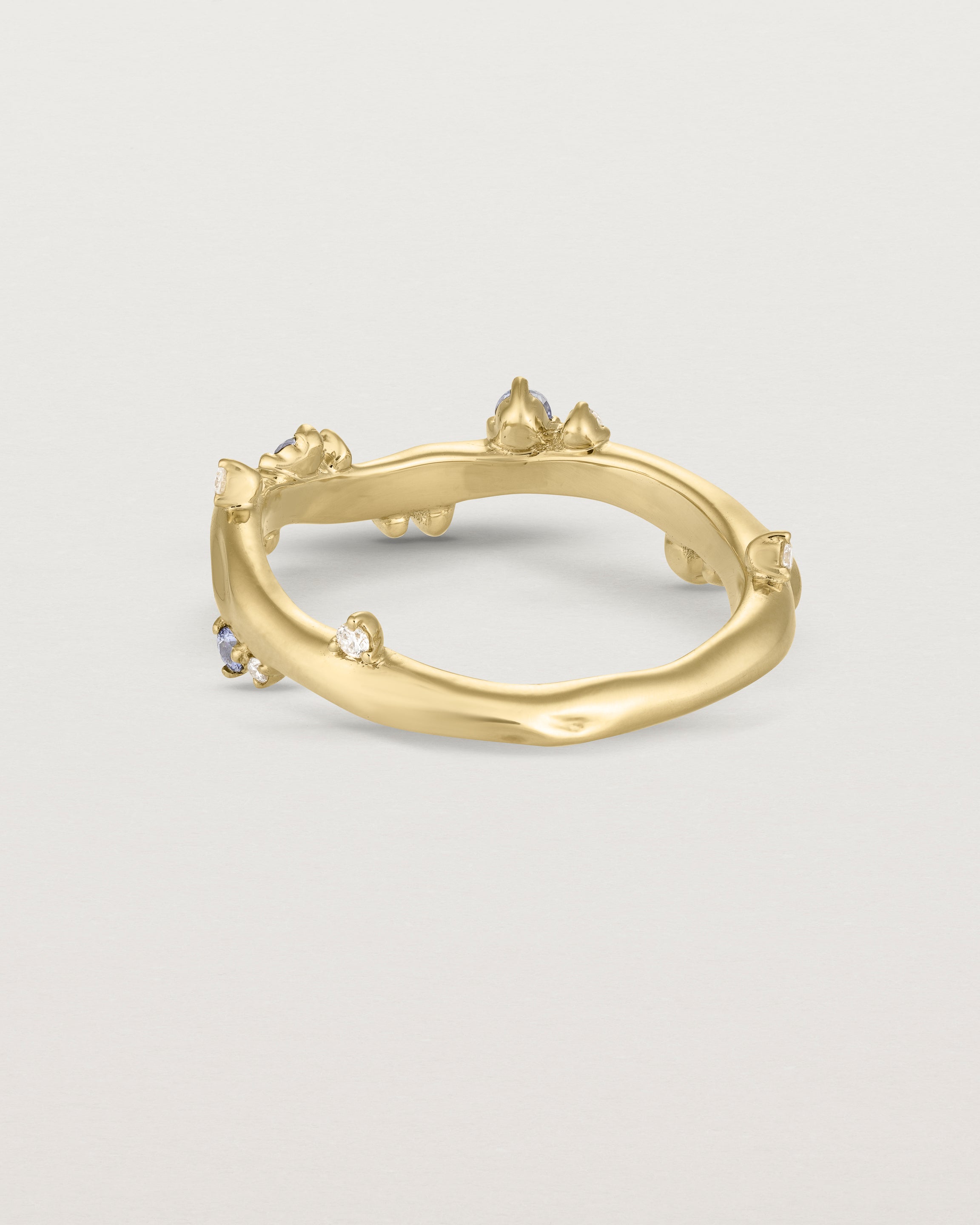 back image of the Ember ring in yellow gold featuring a scattering of white diamonds and blue sapphires.