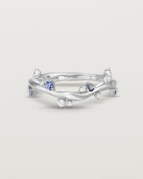 Front image of the Ember ring in white gold featuring a scattering of white diamonds and blue sapphires.