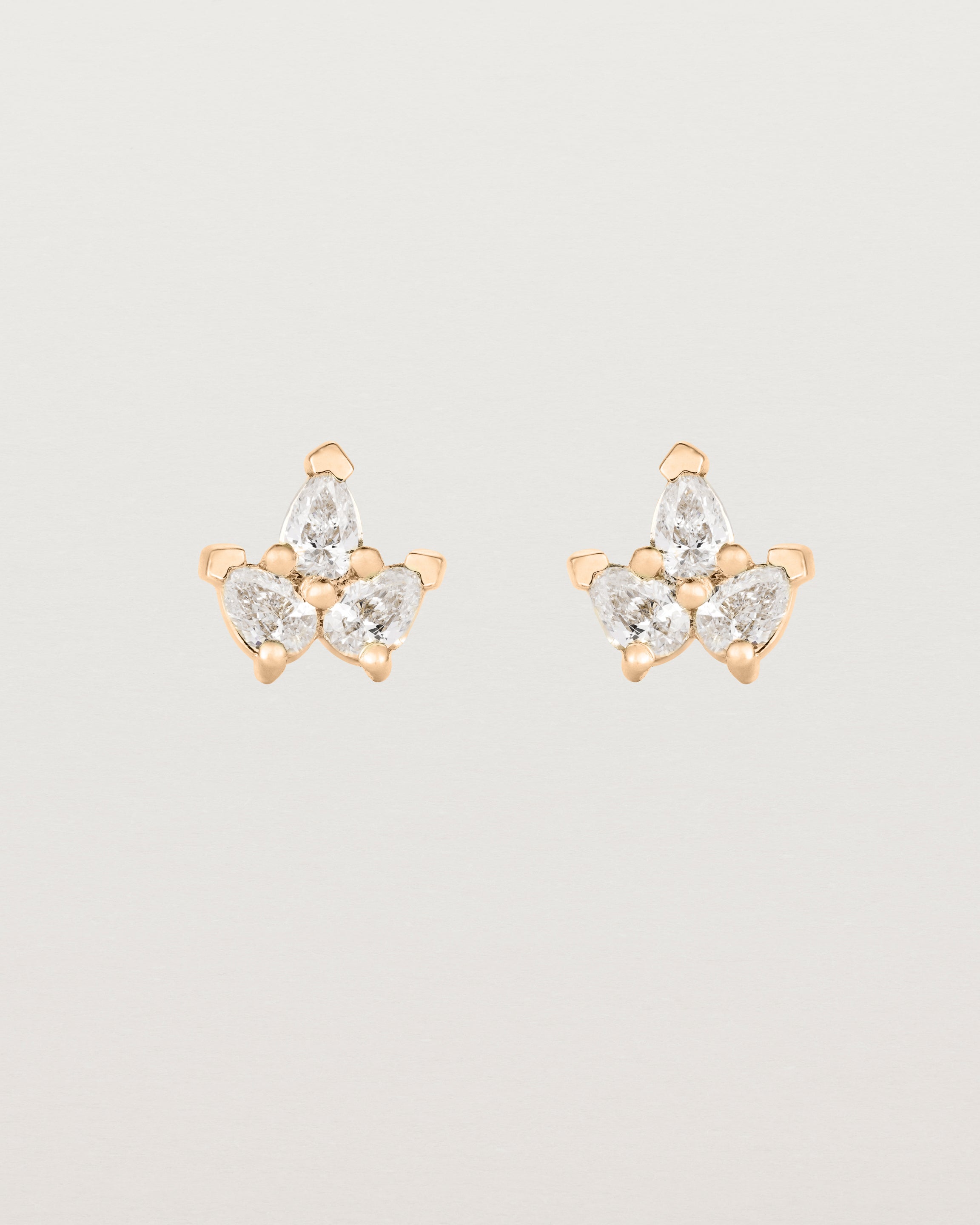 A pair of rose gold studs featuring three pear shaped diamonds