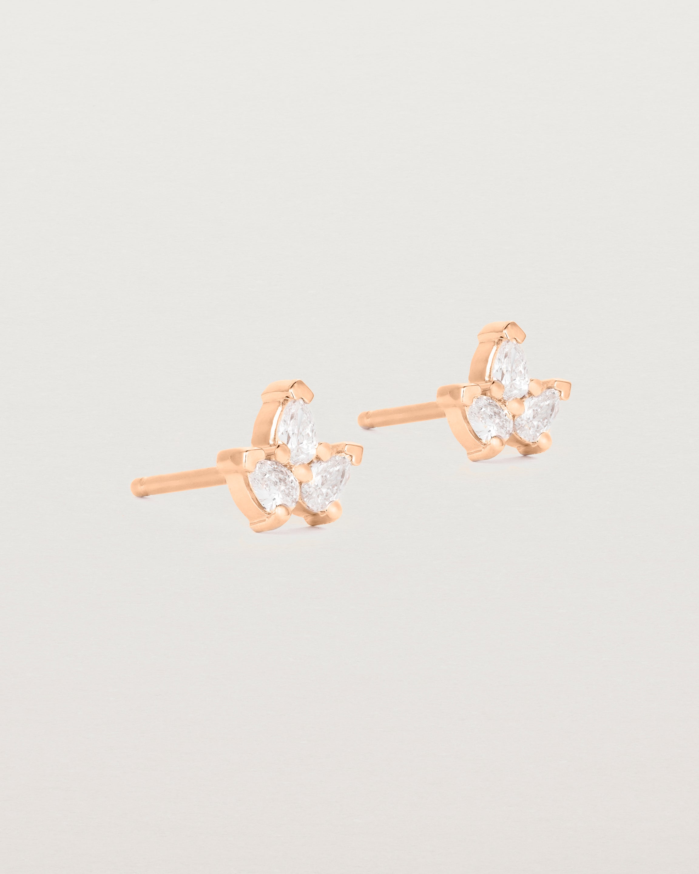 A pair of rose gold studs featuring three pear shaped diamonds