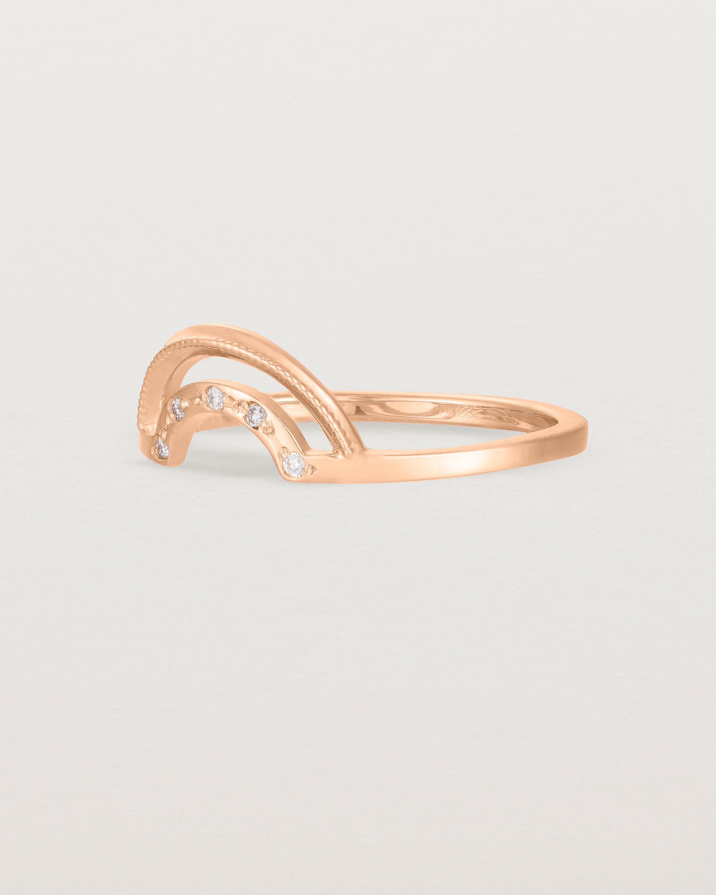 The side view of a double arc crown ring with white diamonds adoring the inner arc - crafted in rose gold. 