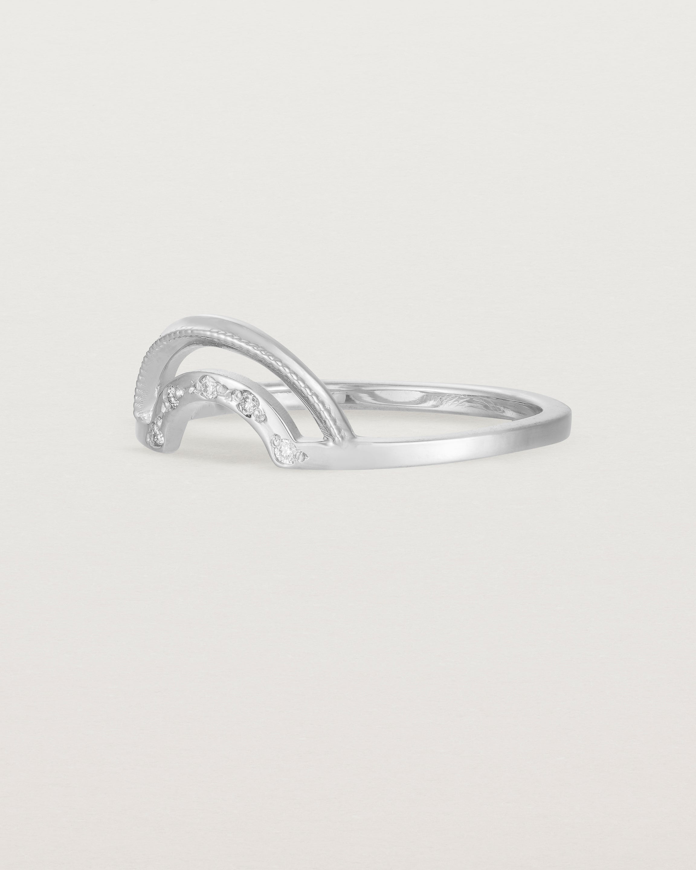 The side view of a double arc crown ring with white diamonds adoring the inner arc - crafted in white gold. 