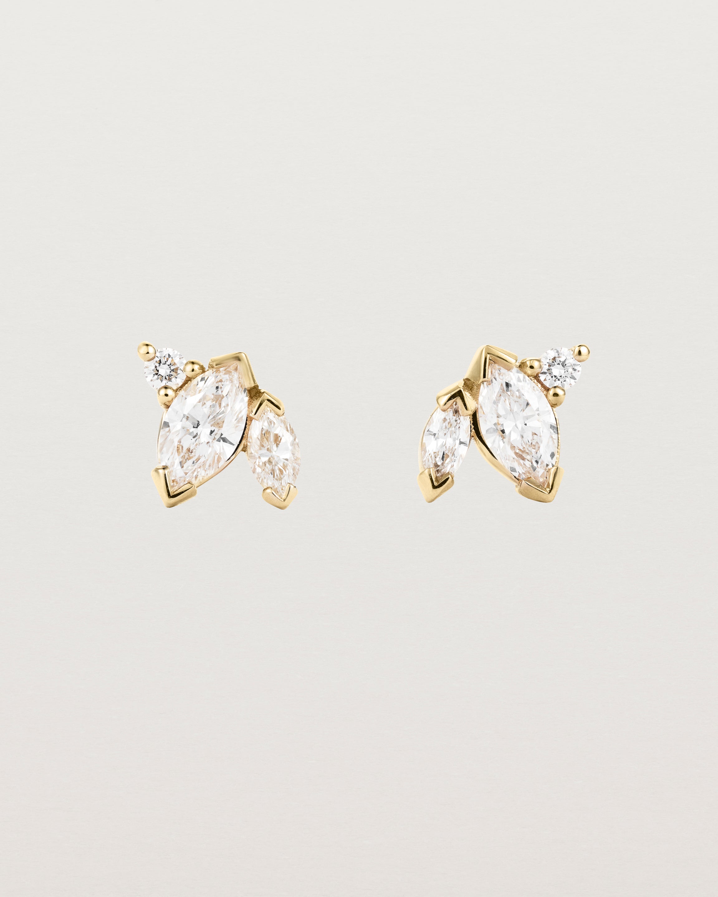 A pair of yellow gold studs featuring two marquise and one round diamond