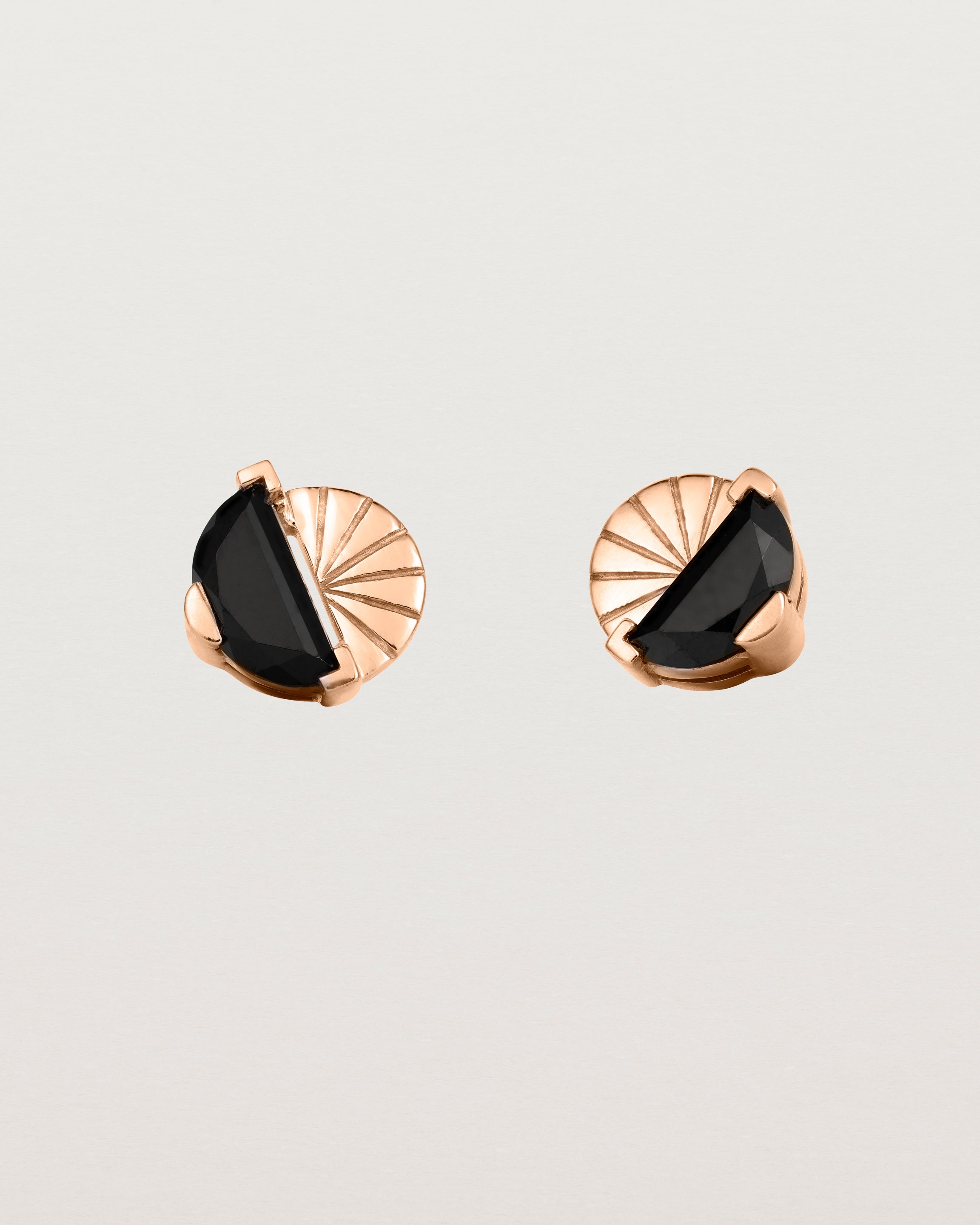A pair of rose gold studs featuring a half moon cut black spinel