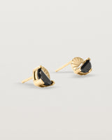 A pair of yellow gold studs featuring a half moon cut black spinel