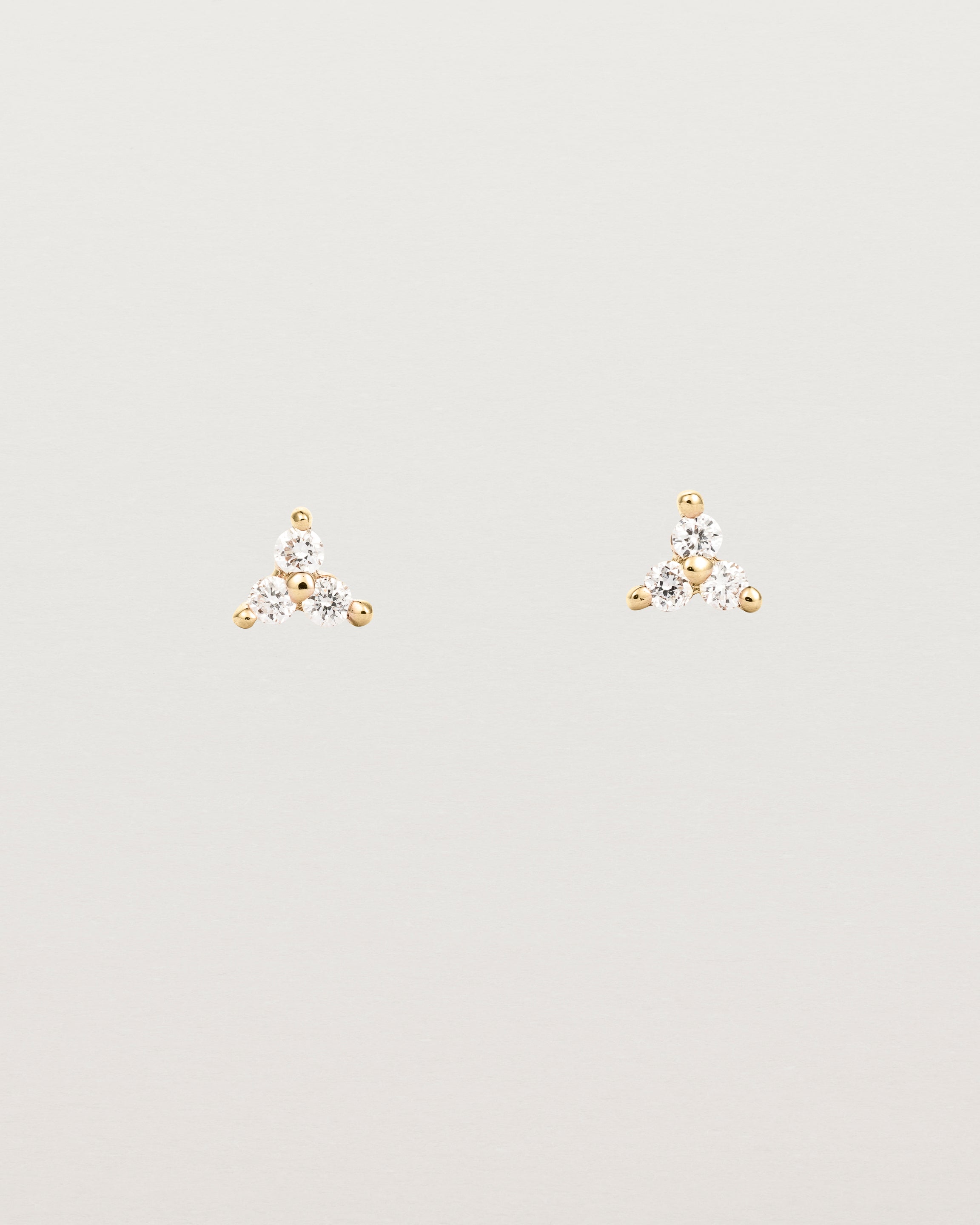 A pair of small yellow gold studs with three small white diamonds.