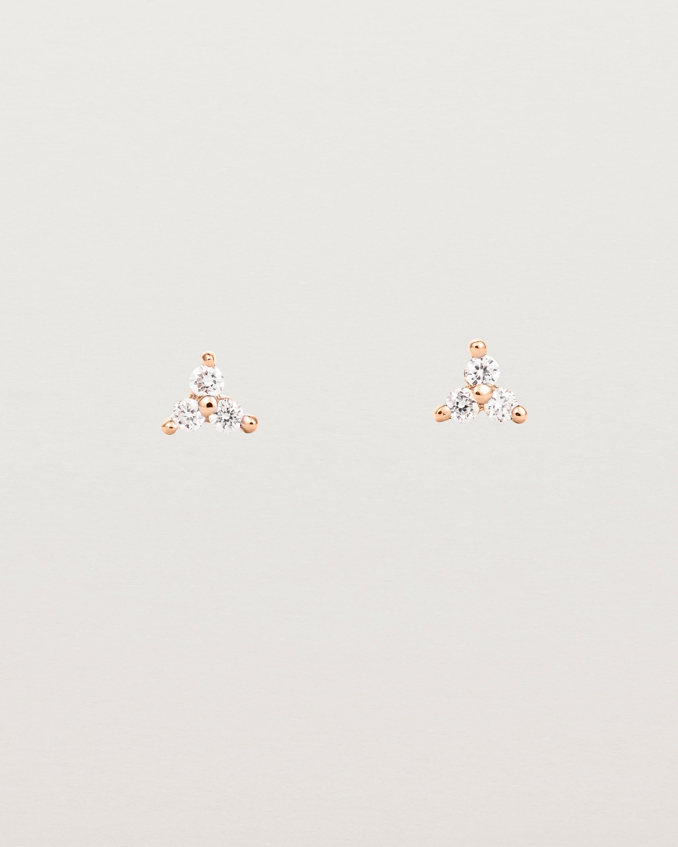 A pair of rose gold studs with three small white diamonds.