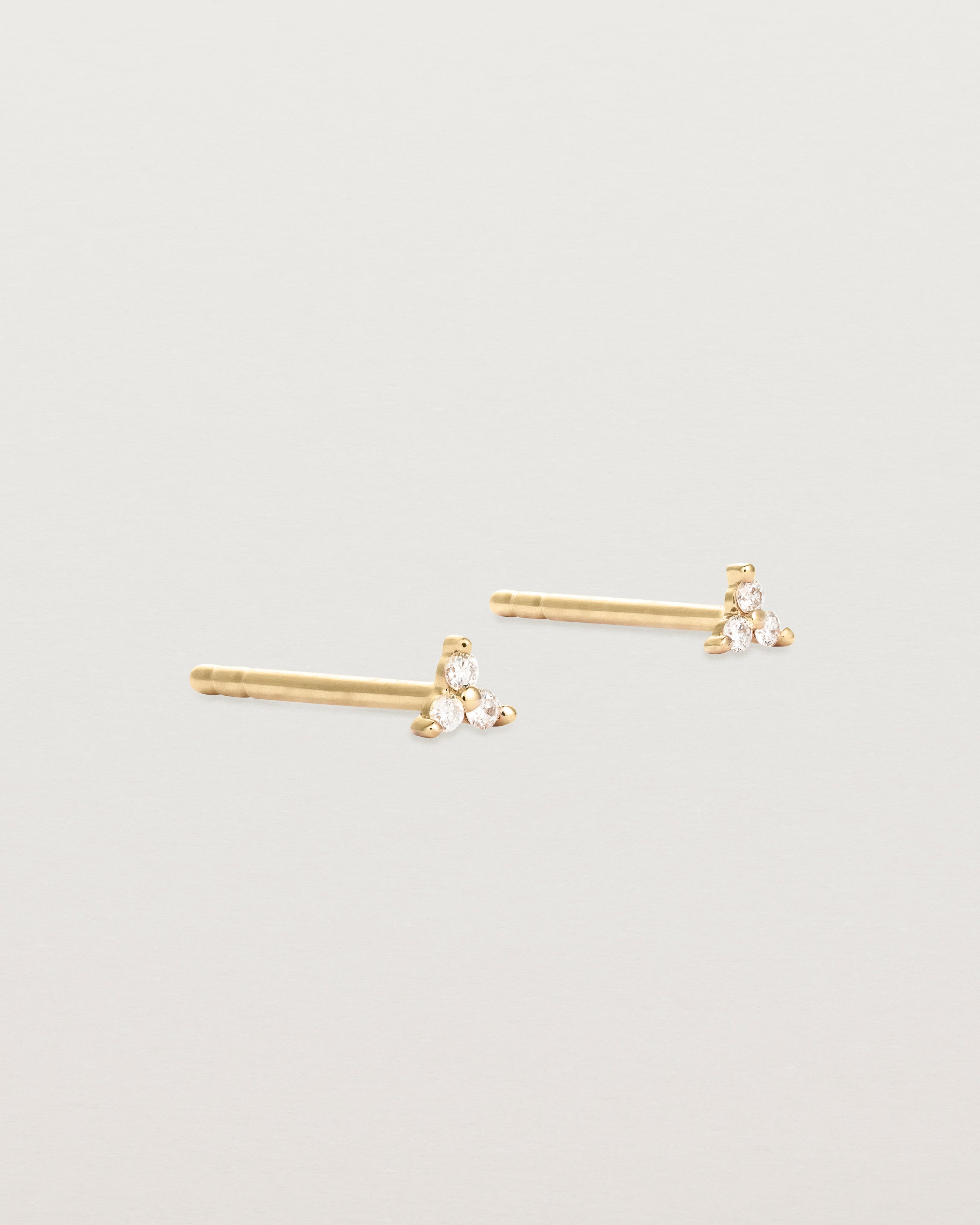 A pair of small yellow gold studs with three small white diamonds.