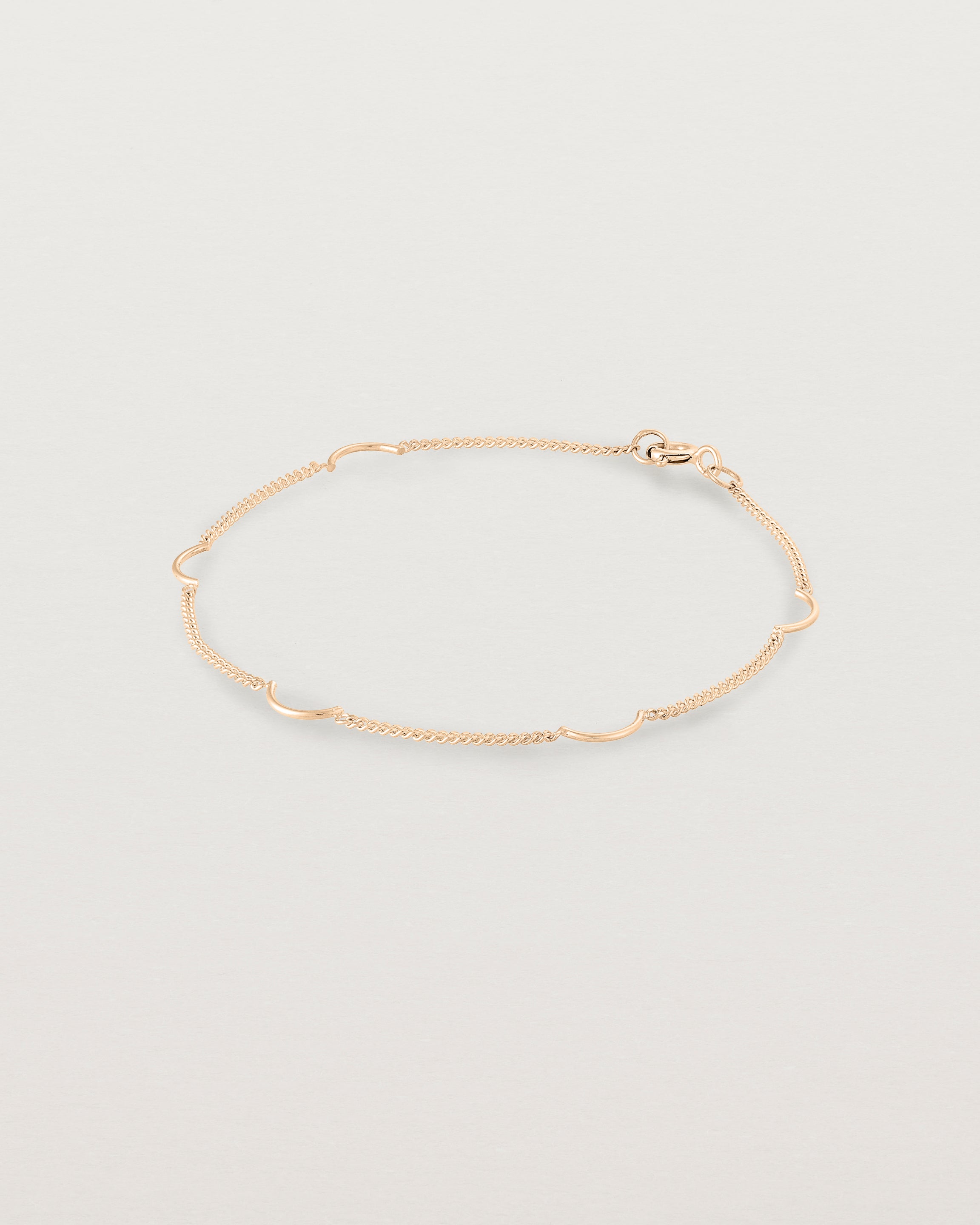 A rose gold chain bracelet with five gold arcs