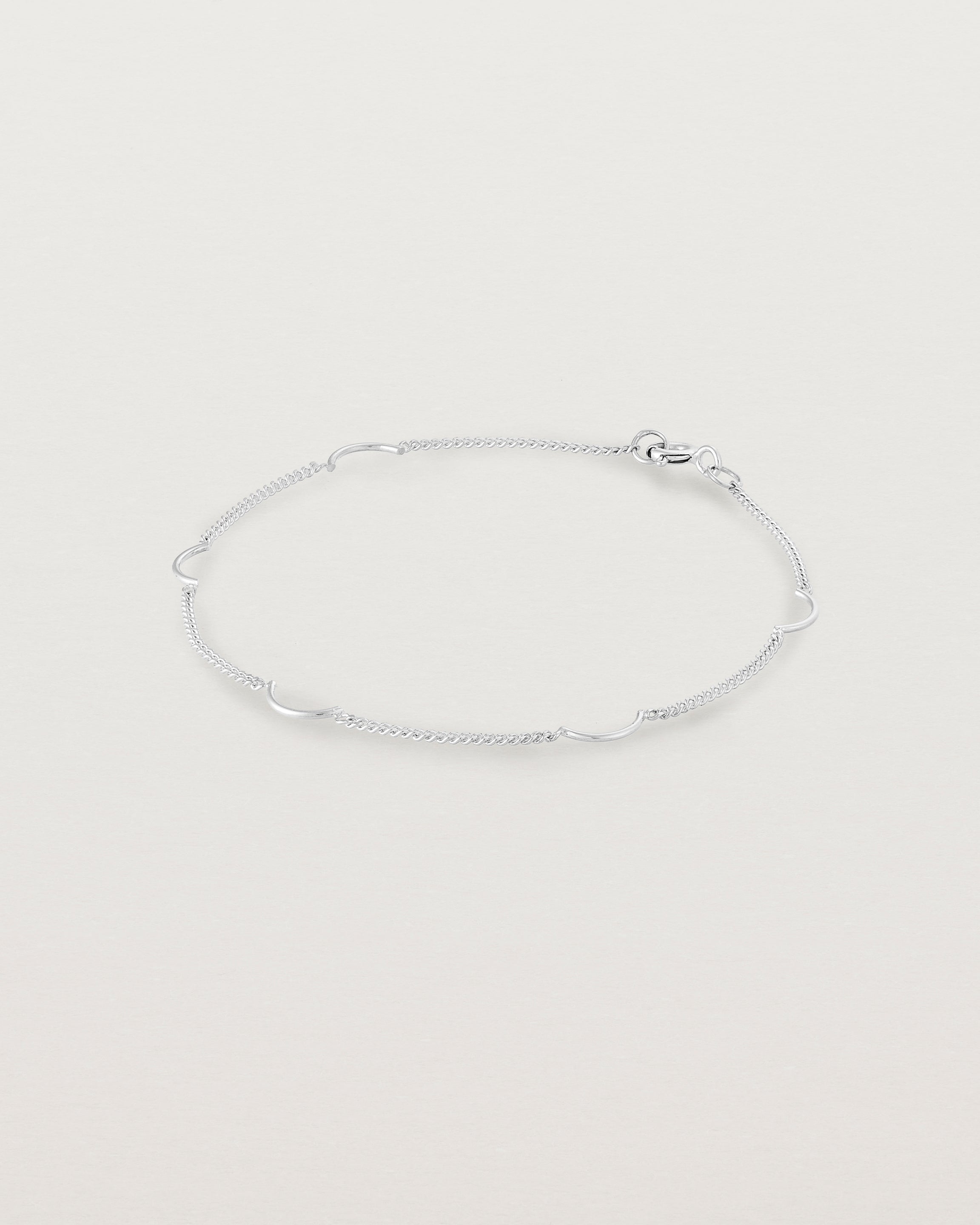 A silver chain bracelet with five gold arcs