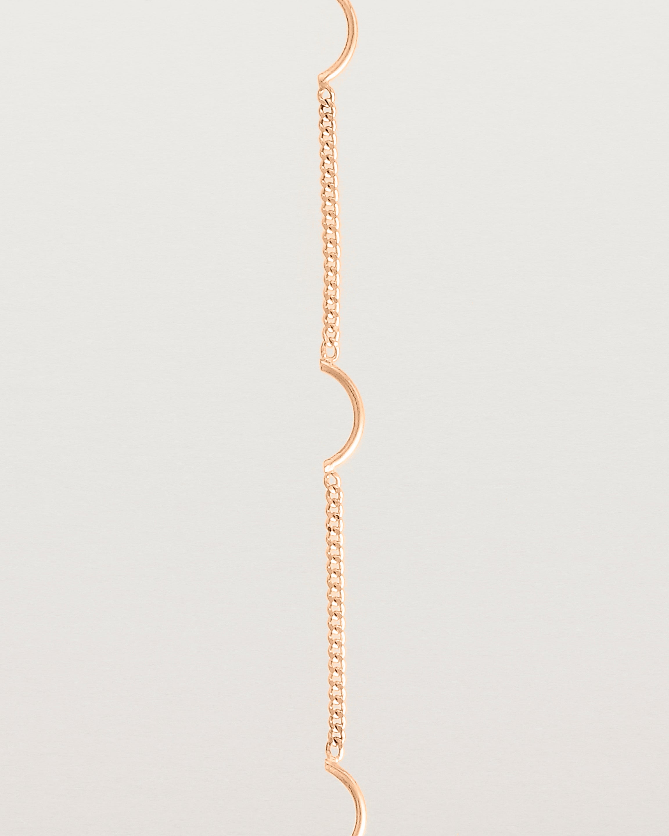 A rose gold chain bracelet with five gold arcs