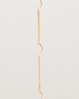A rose gold chain bracelet with five gold arcs