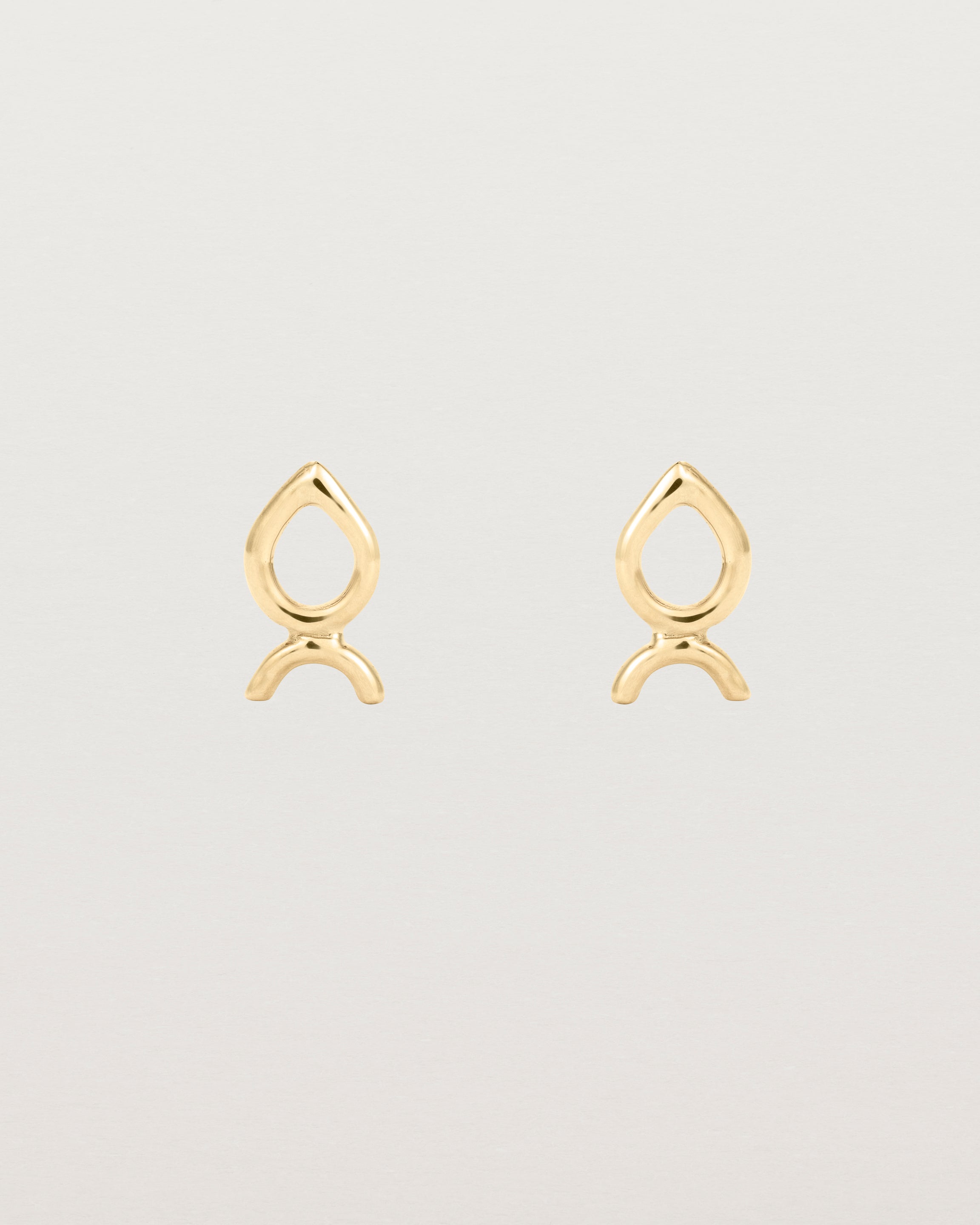 A small pair of yellow gold studs shaped like a tear drop