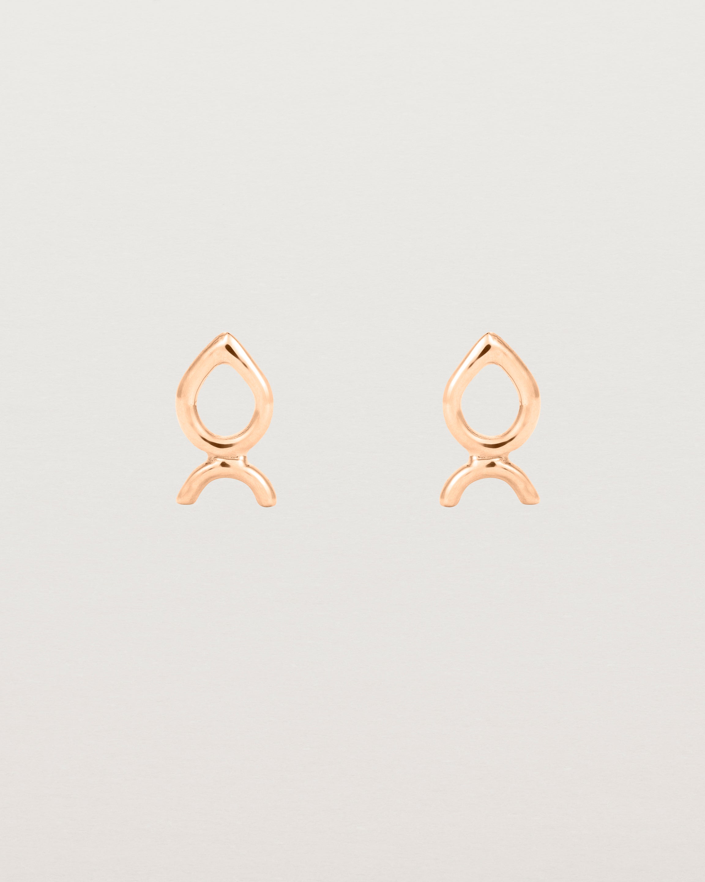 A small pair of rose gold studs shaped like a tear drop