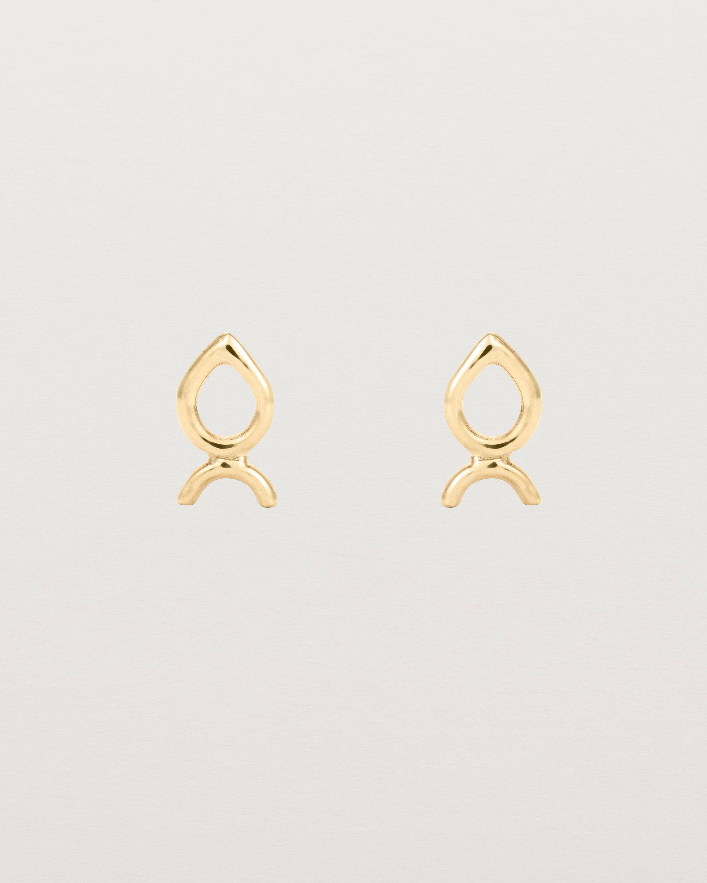 A small pair of yellow gold studs shaped like a tear drop