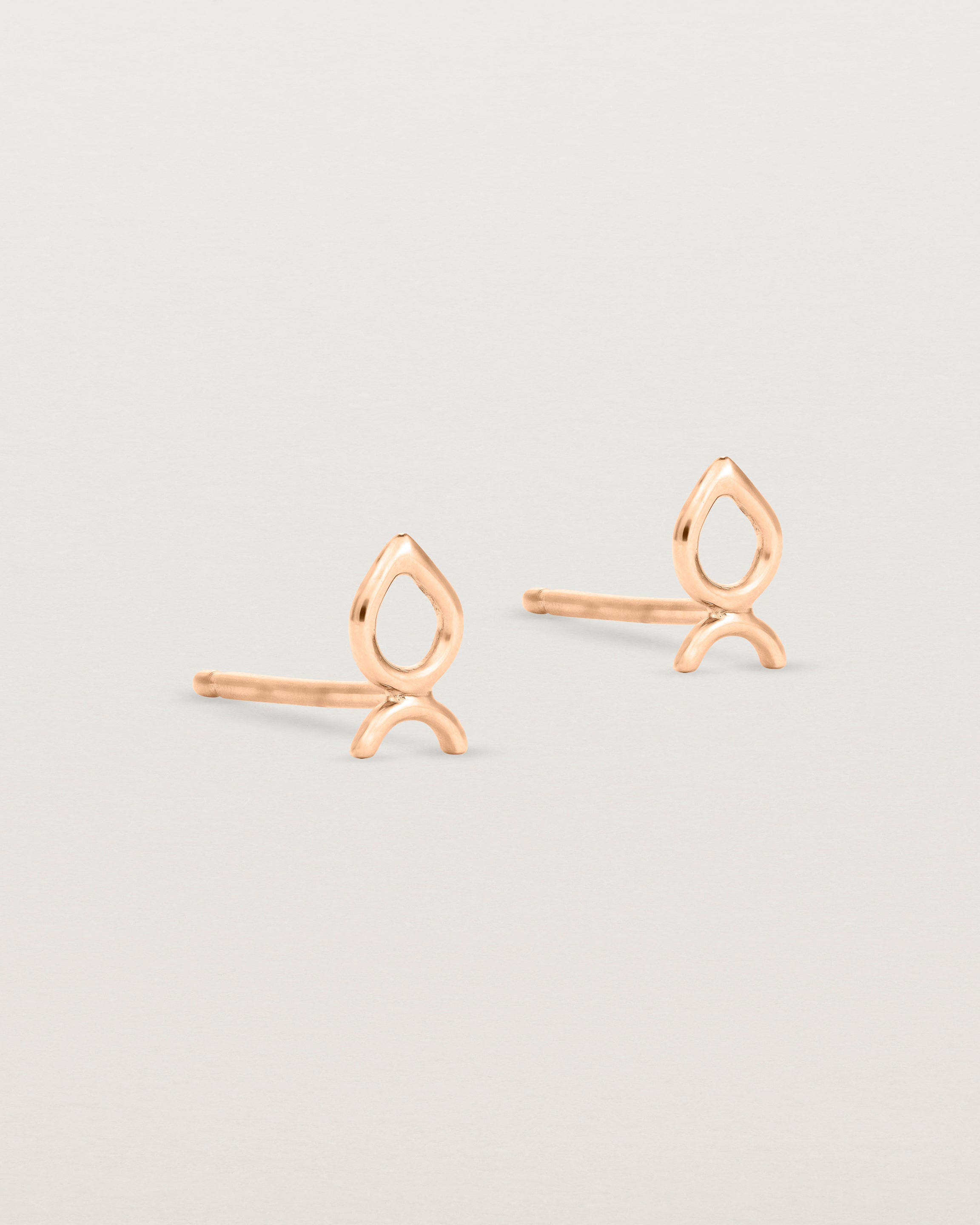 A small pair of rose gold studs shaped like a tear drop