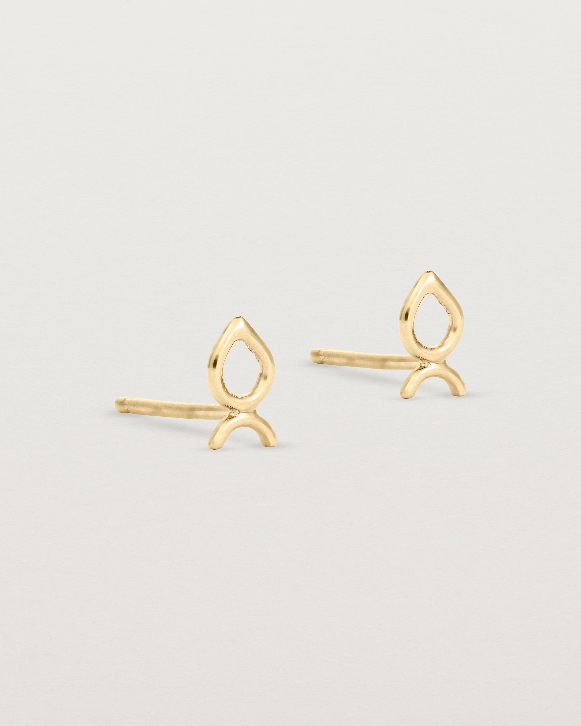 A small pair of yellow gold studs shaped like a tear drop
