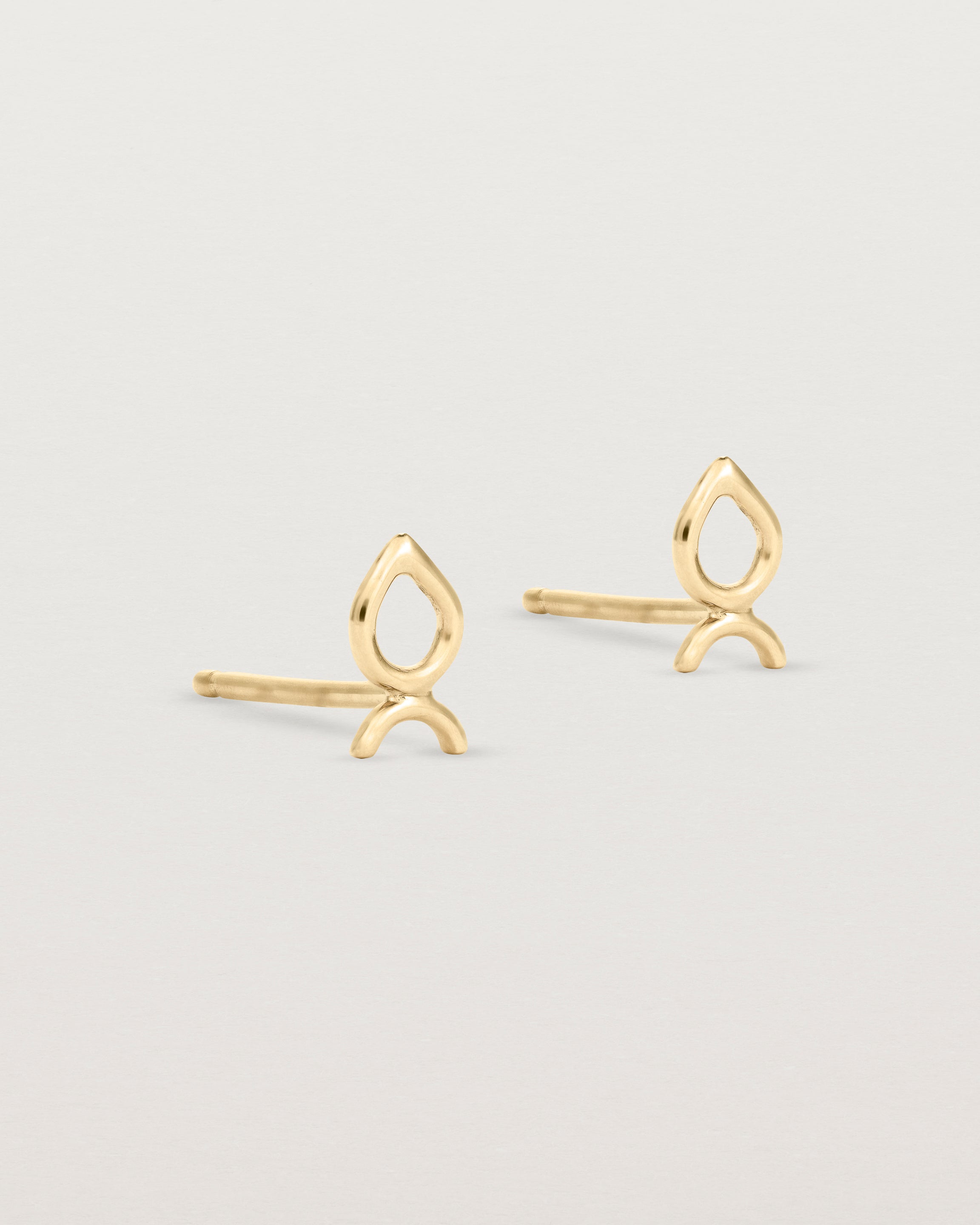 A small pair of yellow gold studs shaped like a tear drop