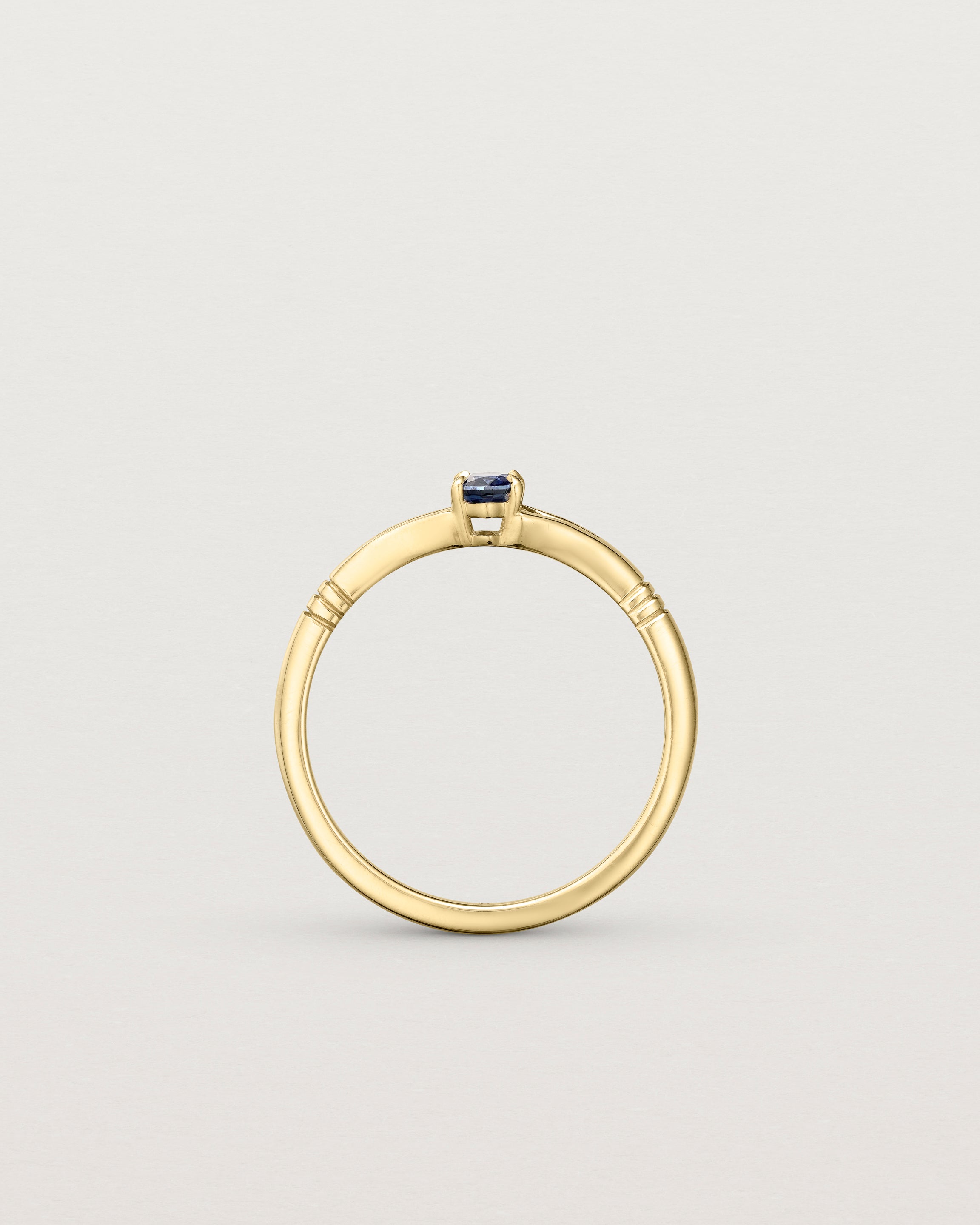 Standing deep etched image of a yellow gold engagement ring with an oval sapphire stone