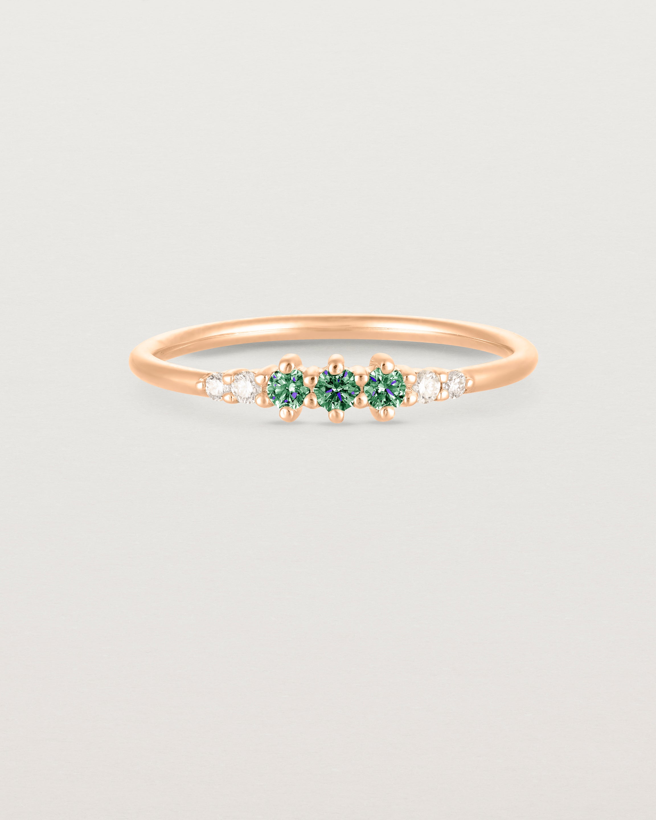 Front facing deep etched image of a rose gold ring with alexandrite birthstones and diamonds.