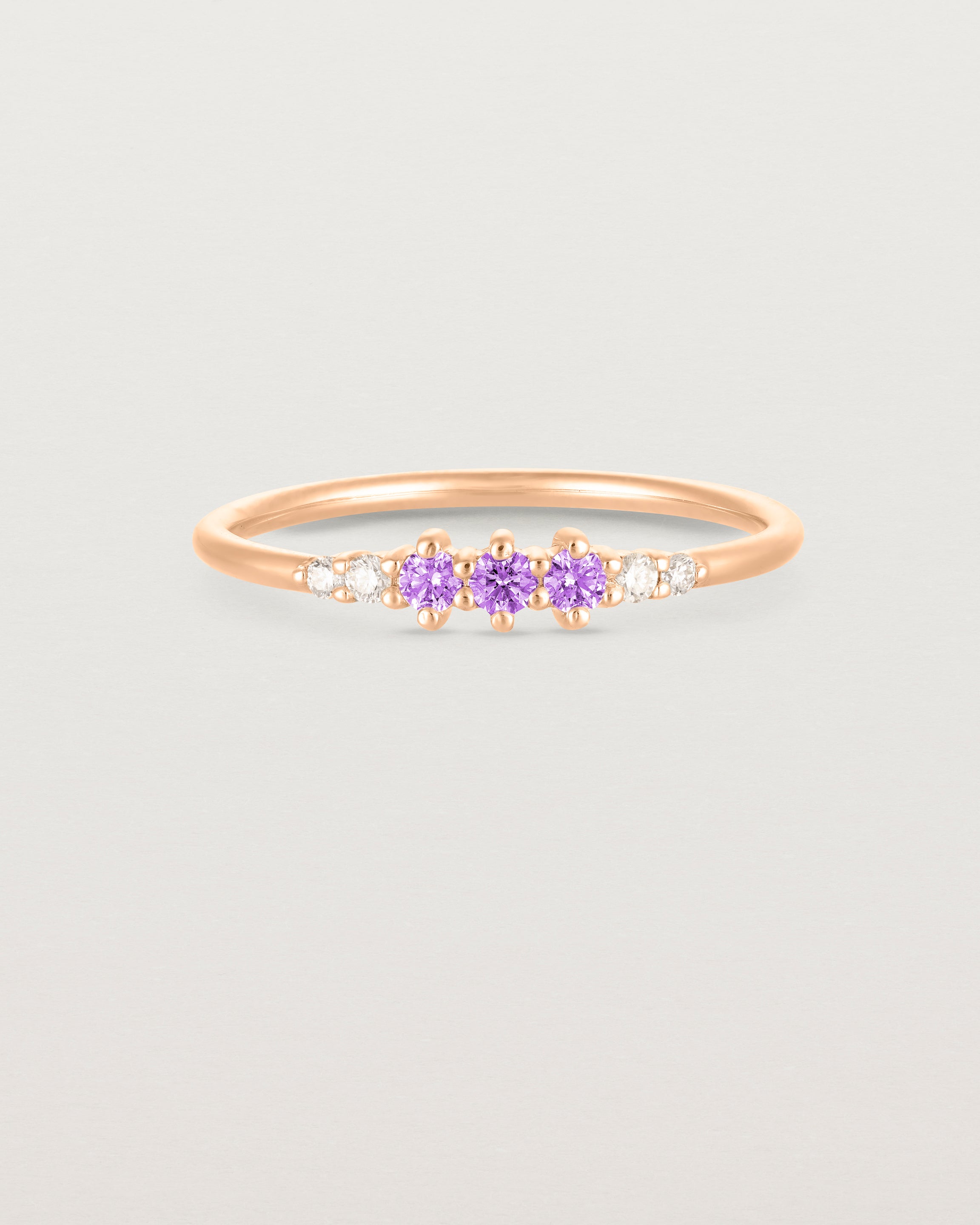 Front facing deep etched image of a rose gold ring with amethyst birthstones and diamonds.