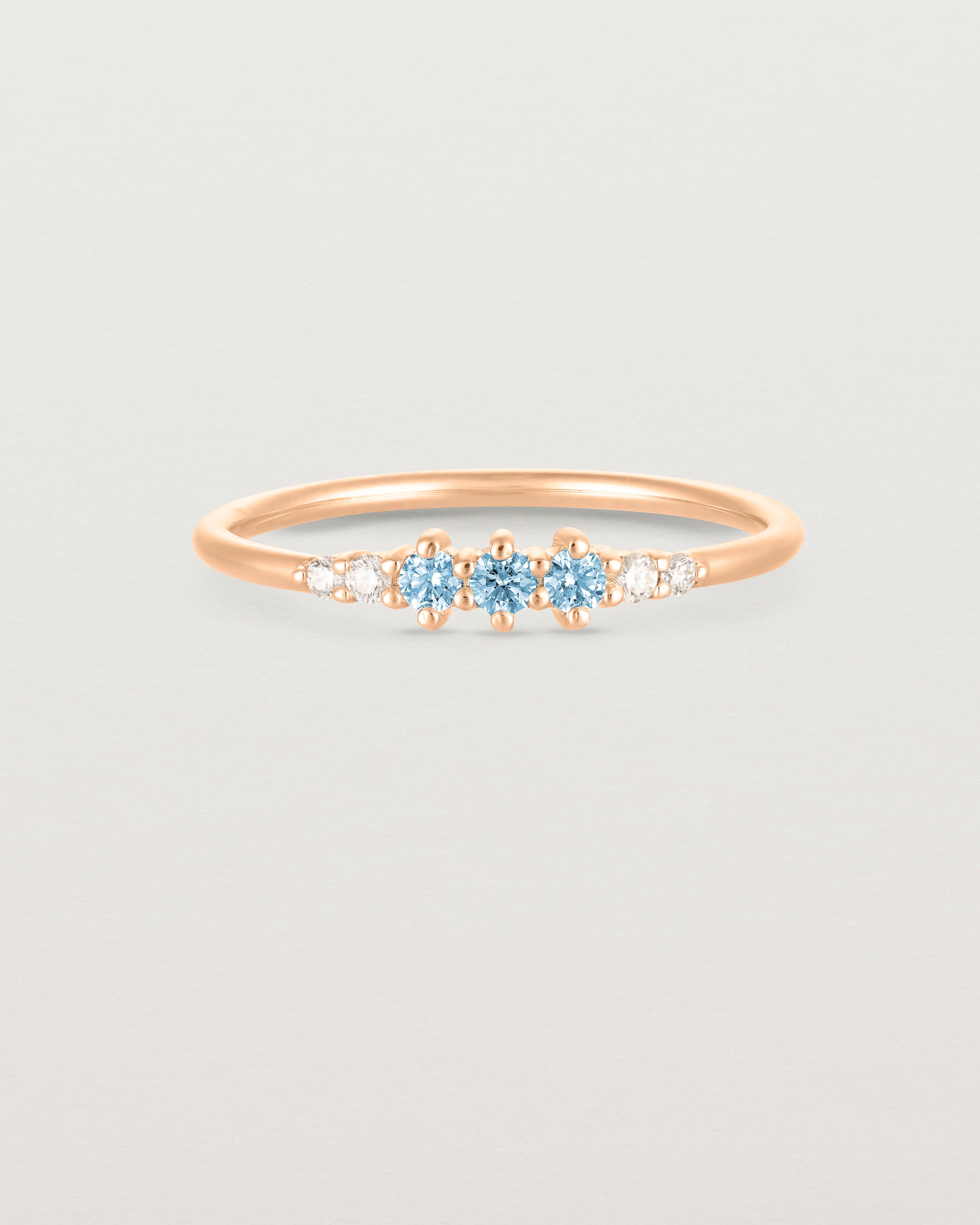 Front facing deep etched image of a rose gold ring with aquamarine birthstones and diamonds.