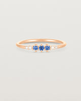 Front facing deep etched image of a rose gold ring with blue sapphire birthstones and diamonds.