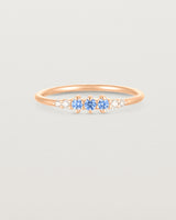 Front facing deep etched image of a rose gold ring with blue topaz birthstones and diamonds.