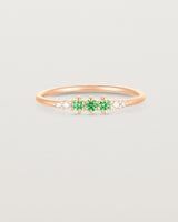 Front facing deep etched image of a rose gold ring with emerald birthstones and diamonds.