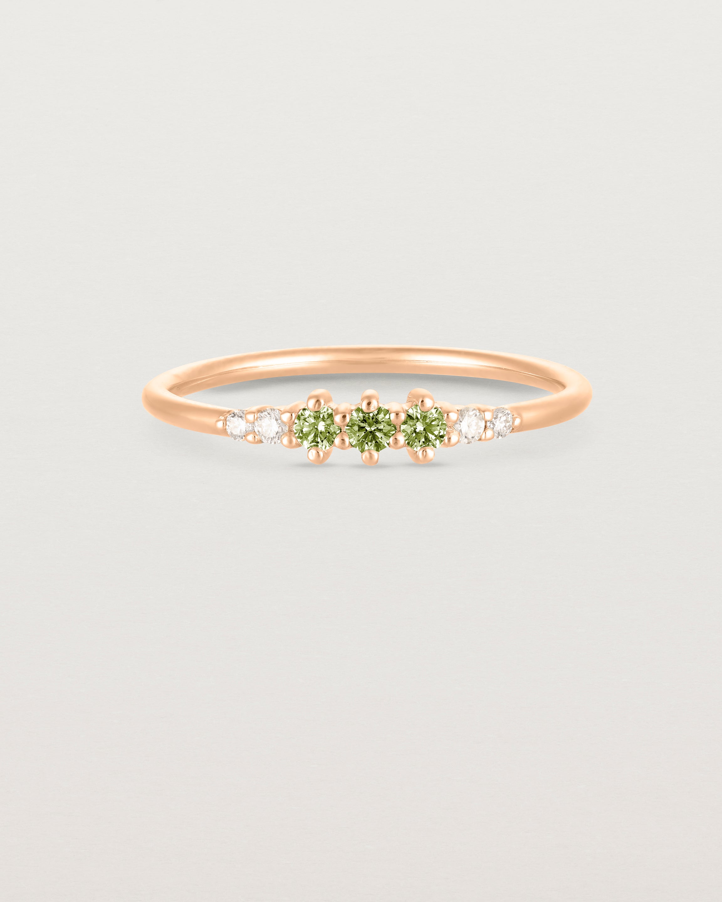 Front facing deep etched image of a rose gold ring with peridot birthstones and diamonds.
