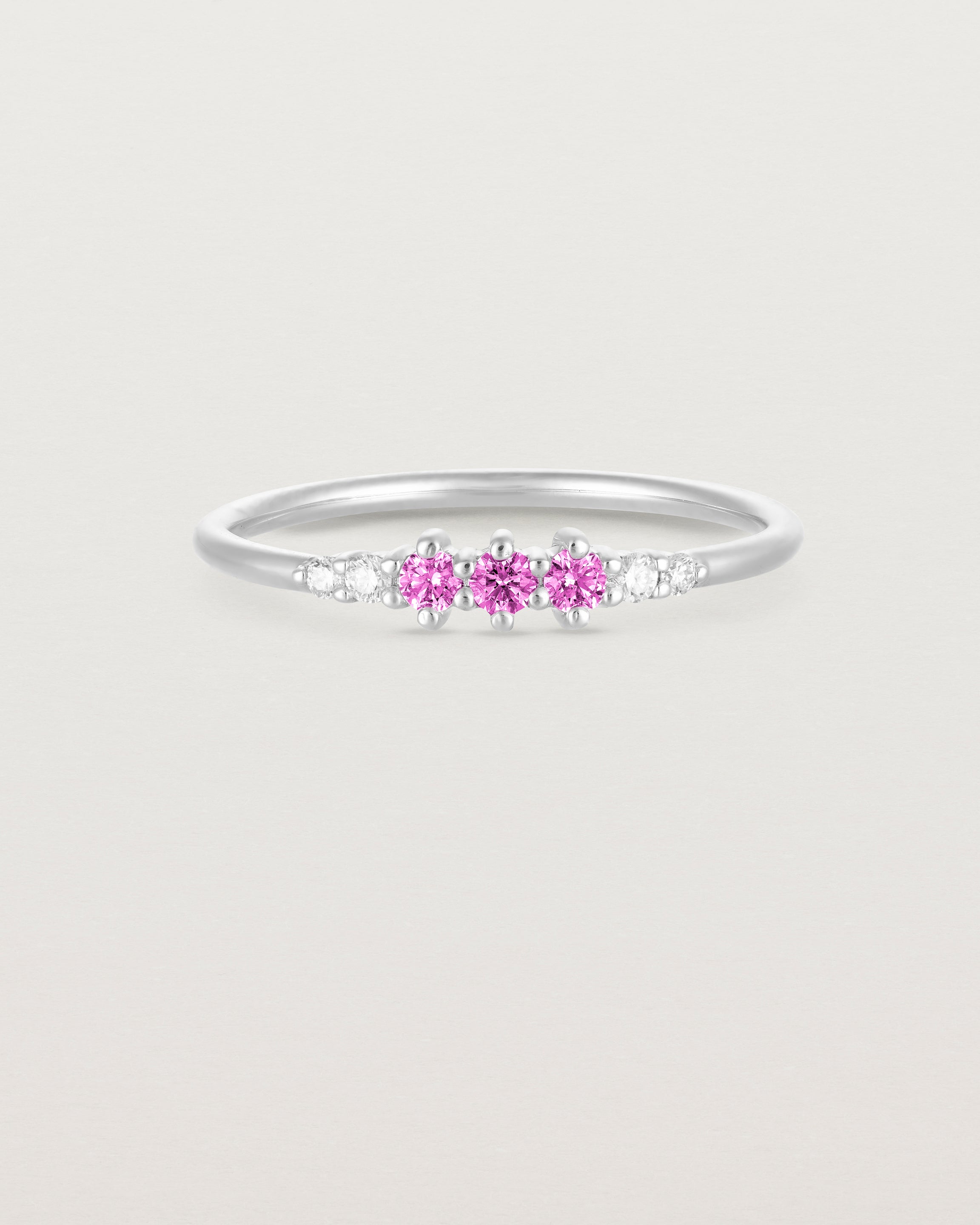 Front facing deep etched image of a white gold ring with pink tourmaline birthstones and diamonds.