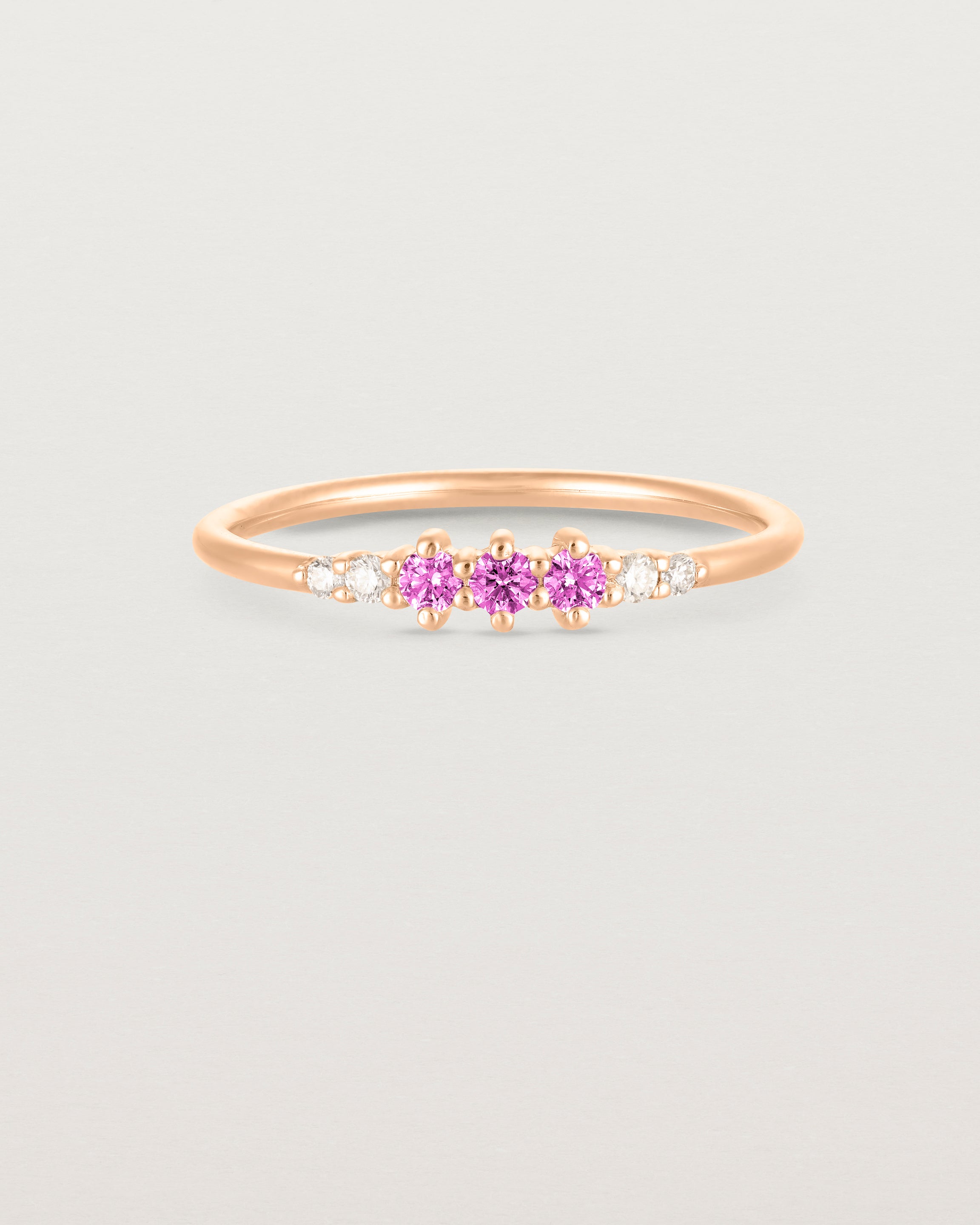 Front facing deep etched image of a rose gold ring with pink tourmaline birthstones and diamonds.